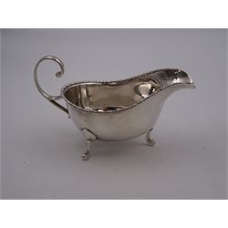Pair of 1930s silver sauce boats, of typical plain form, each with bead and dart rim and flying scroll handles, upon three pad feet, hallmarked Walker & Hall, Birmingham 1935