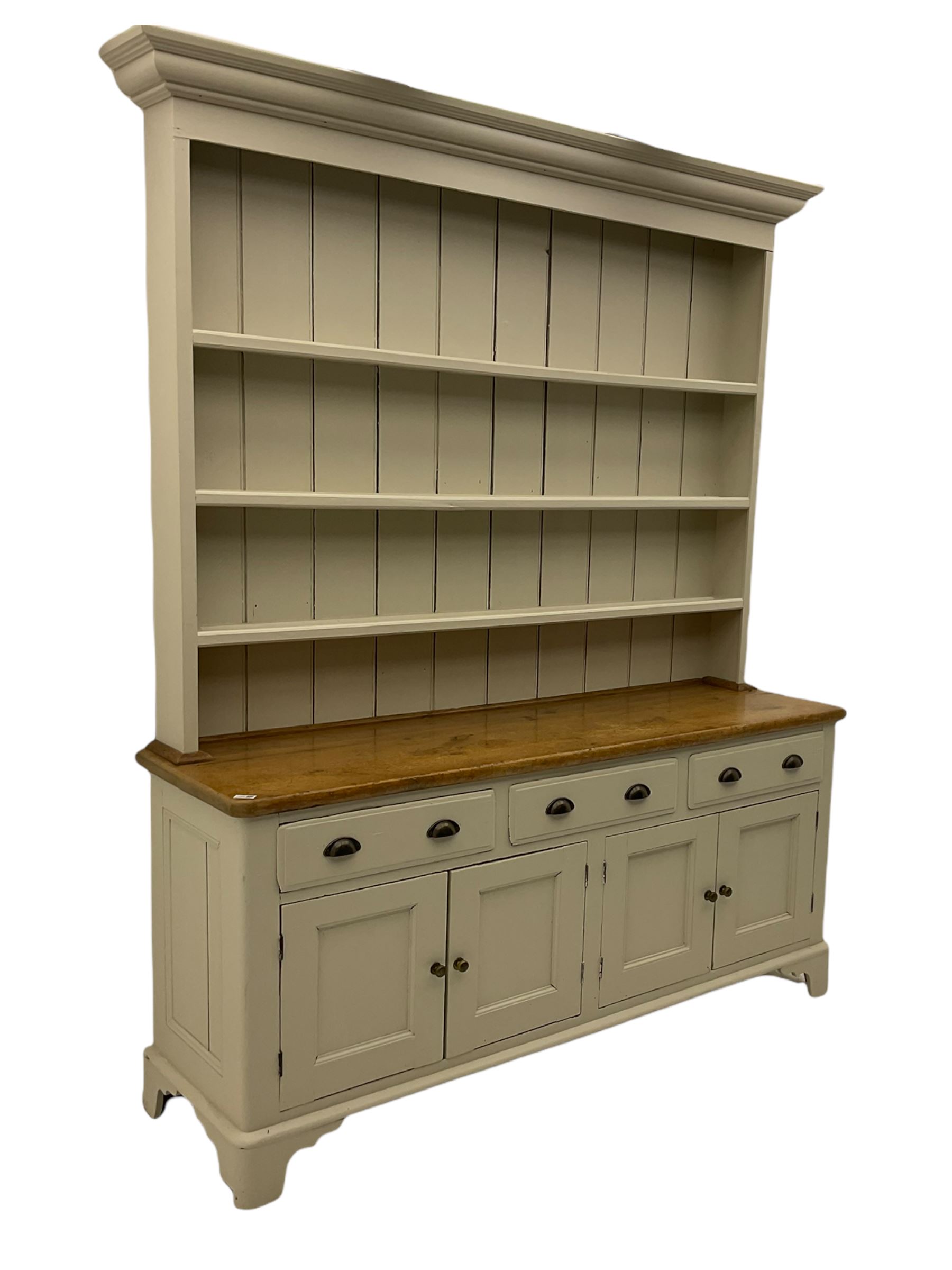 Victorian pine dresser, raised painted three heights plate rack with projecting cornice, waxed top over pained base fitted with three drawers and two double cupboards, bracket feet
