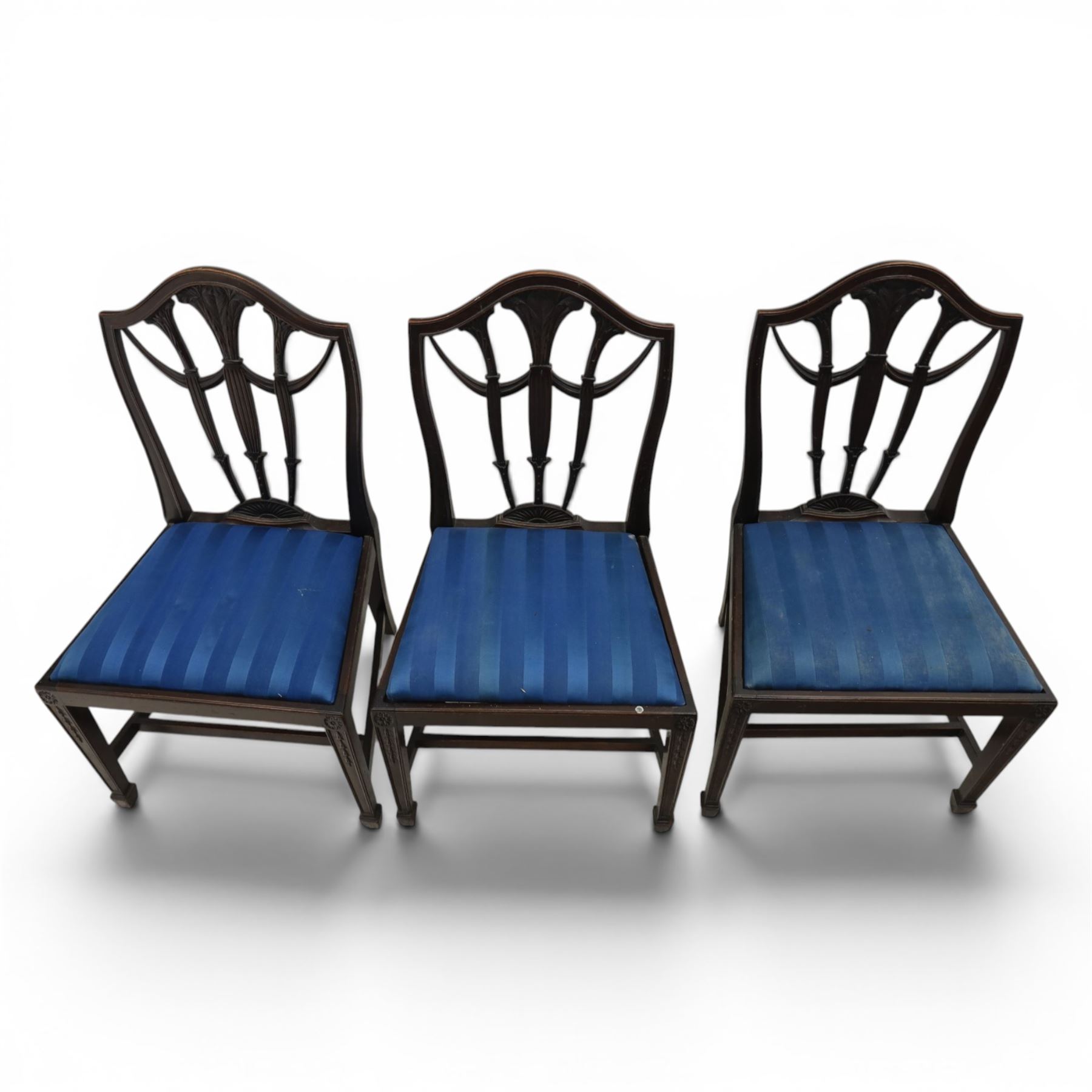 Set of eight George III style mahogany dining chairs, comprising two carvers and six singles, each with shaped top rail above pierced splay carved with feathers, with drop in stuffover seats upholstered in blue striped fabric, raised upon square tapering legs joined by stretchers, together with a mahogany twin pedestal dining table, the oval top with central leaf raised upon turned columns and splayed reeded legs terminating in lion paw feet and brass castors, 