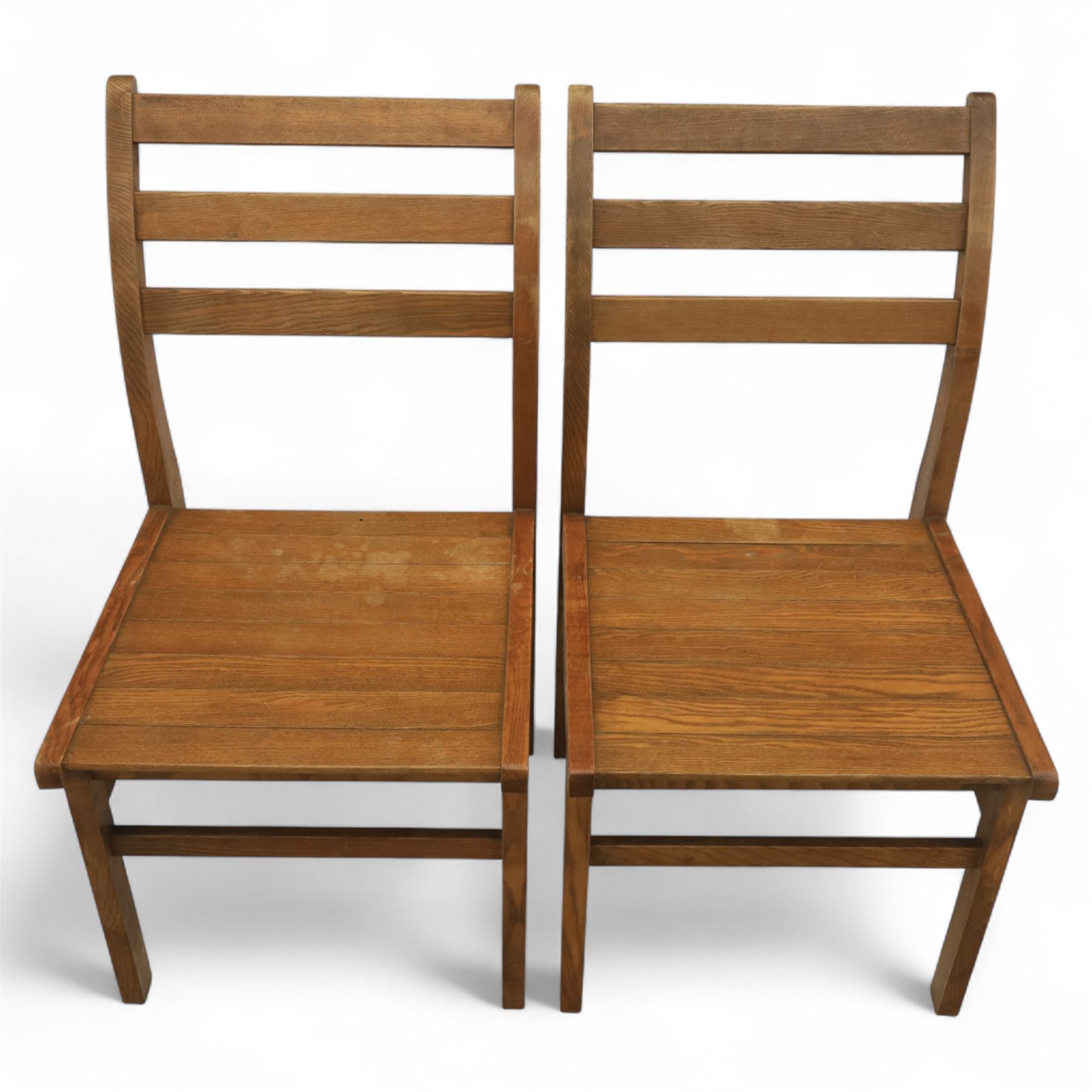 Treske of Thirsk - solid oak refectory dining suite, rectangular top with chamfered edge over trestle base united by a central stretcher, together with six matching slat back dining chairs, including two carvers, with panelled seats and square legs united by stretchers (H 87cm, W 62cm, D 57cm)