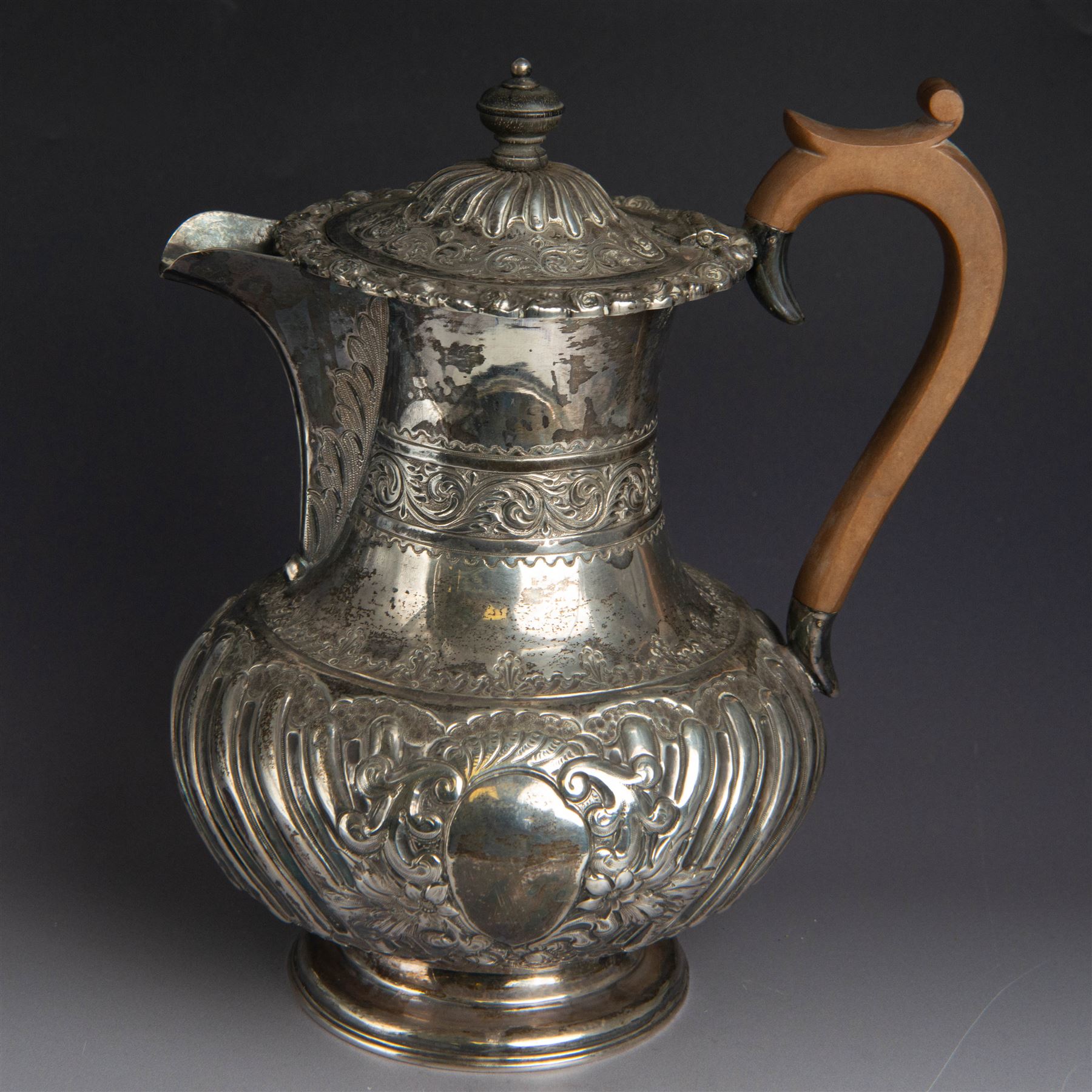 Victorian silver four piece tea service, comprising hot water pot, teapot, milk jug and sugar bowl, of circular part fluted bellied form, with embossed and engraved floral decoration, engraved with initials to body, the teapot and hot water pot with wooden handles and finials, hallmarked Z Barraclough & Sons, Sheffield 1898