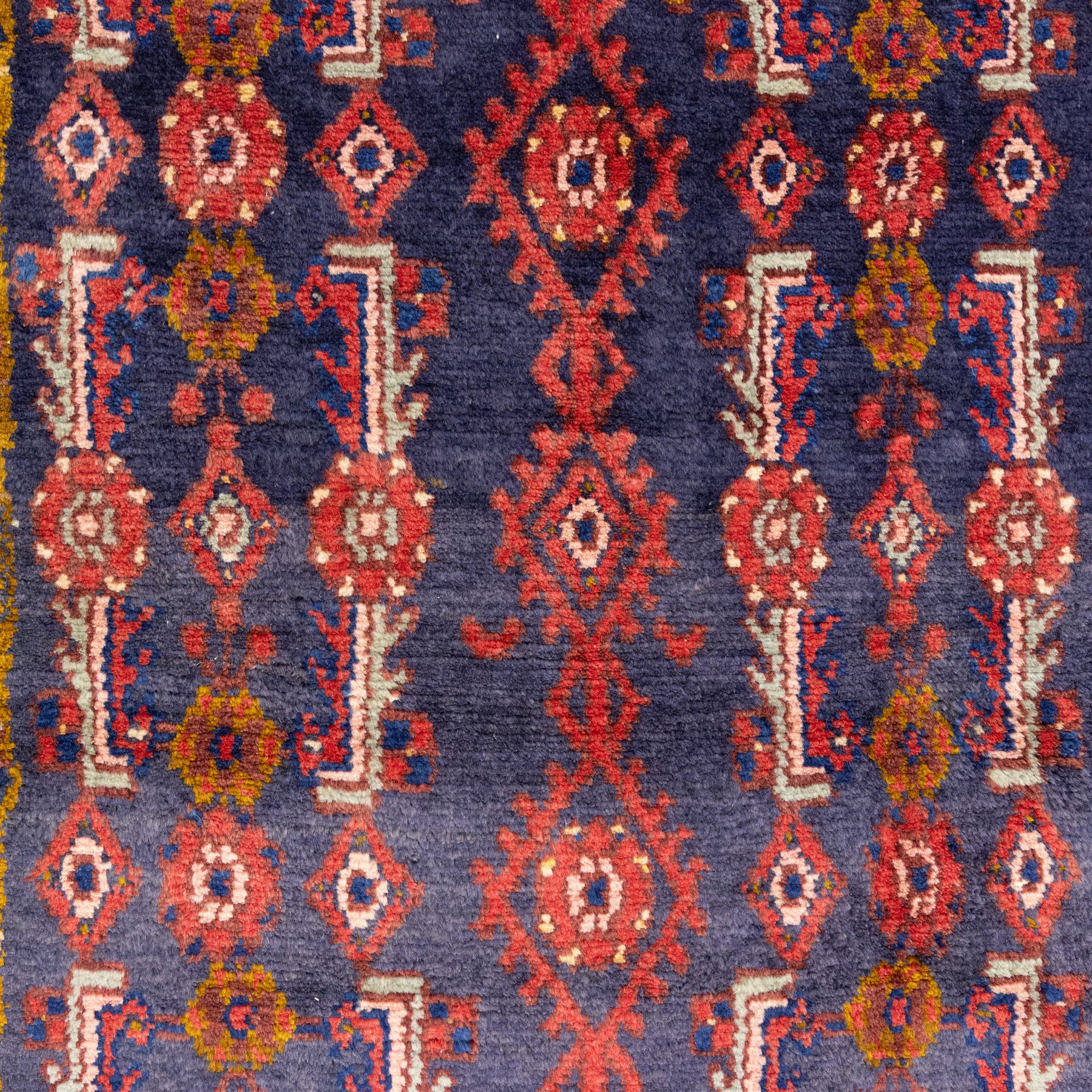 North West Persian Cirjan hand-knotted rug, indigo field decorated with vertical columns of stylized boteh, rosettes and diamond devices arranged in a repeating lattice and a chain of linked lozenges, enclosed by a mustard gold inner border and a principal border of madder ground, flanked by narrow guard stripes, with cotton fringe ends 