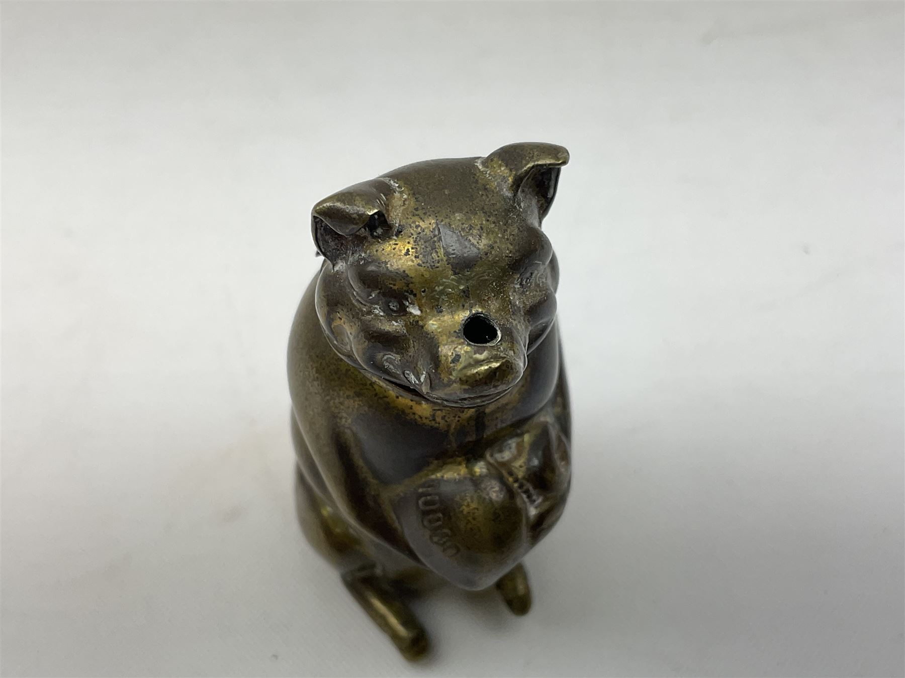 Victorian novelty brass vesta case modelled in the form of a pig holding a money bag, together with a silver vesta, hallmarked 