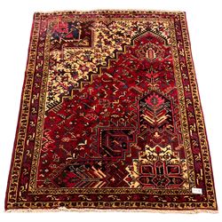 Persian Hamadan red ground rug, decorated with stylised plant motifs, the band border with repeating design
