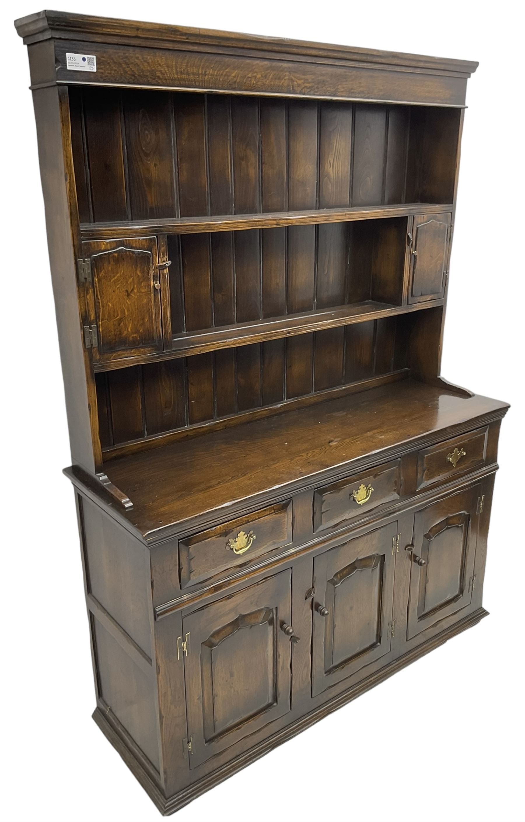 Georgian design oak dresser, the two-tier plate rack with two flanking spice cupboards, the base fitted with three drawers over three arched fielded panelled cupboards, lower moulded edge on block feet