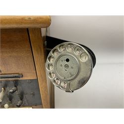 Early-mid 20th century internal telephone system, comprising exchange box with attached TMC rotary telephone and dictograph with Bakelite handset and support upon stained wood case, and 1960s black Bakelite telephone model 312L with G.P.O sticker beneath, largest H30.5cm W36.5cm D30cm