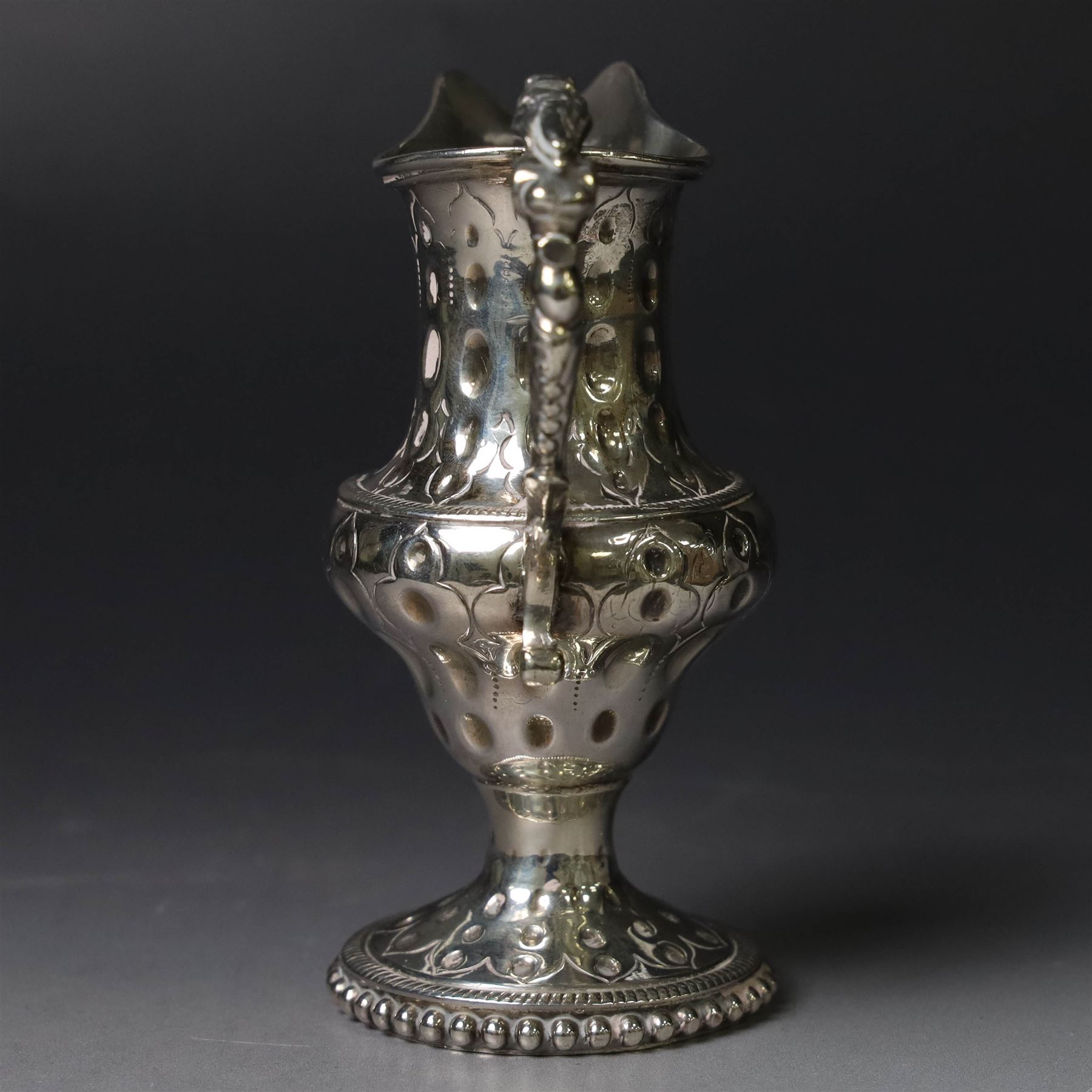 George III silver cream jug, of baluster form with hammered dimpling throughout and scroll handle, upon circular spreading foot with beaded edge, hallmarked Thomas Shepherd, London 1784, H10cm