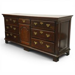 19th century Georgian oak long dresser base, rectangular plank top above a central frieze drawer over a fielded panel cupboard, flanked by three banks with quarter cantered pilasters, brass swan neck handles and escutcheons, raised on shaped bracket feet