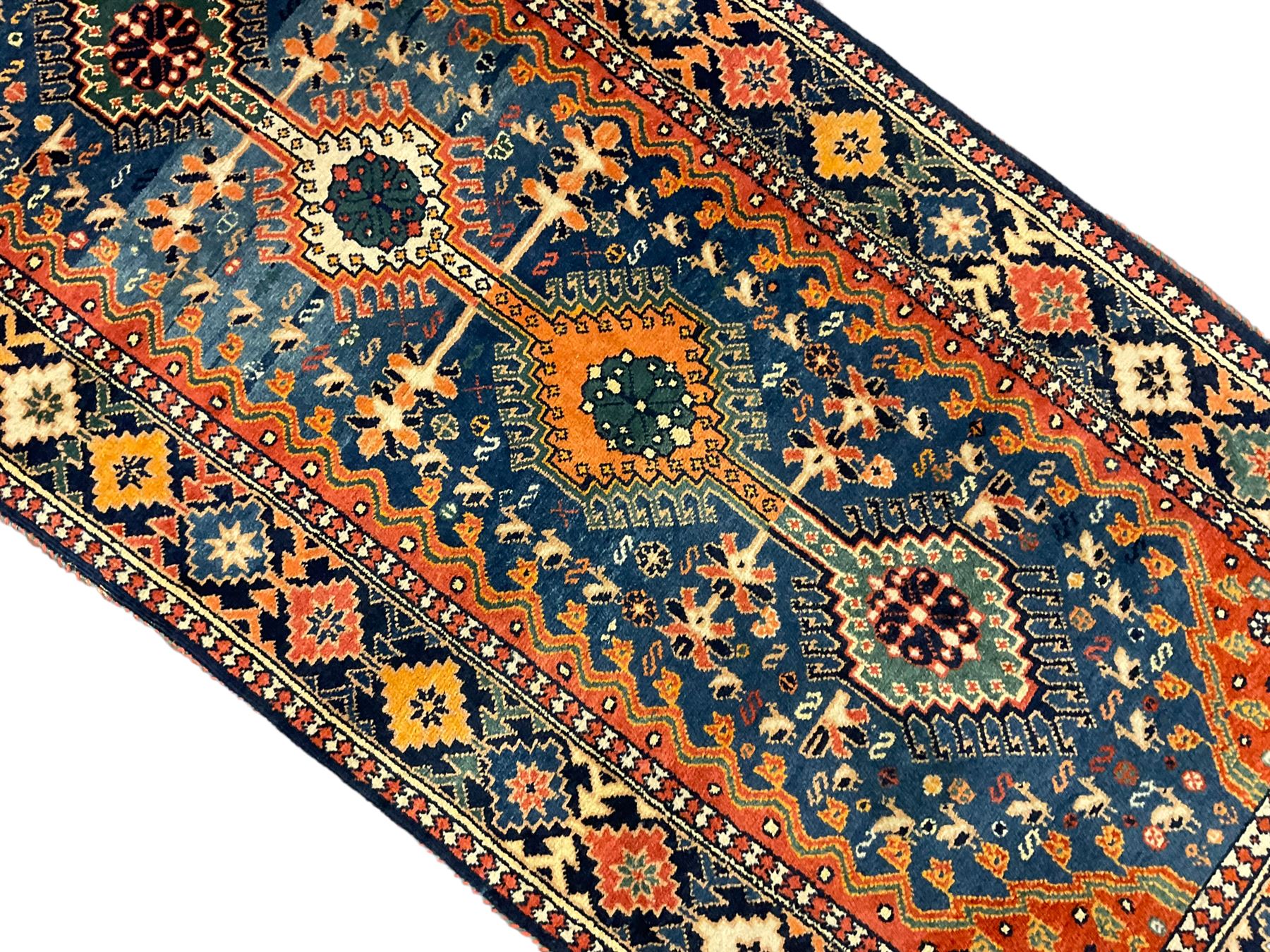Persian blue ground rug, field decorated with four pole medallions with surrounding repeating bird motifs, coral spandrels with flowerheads, guarded border decorated with repeating geometric lozenges