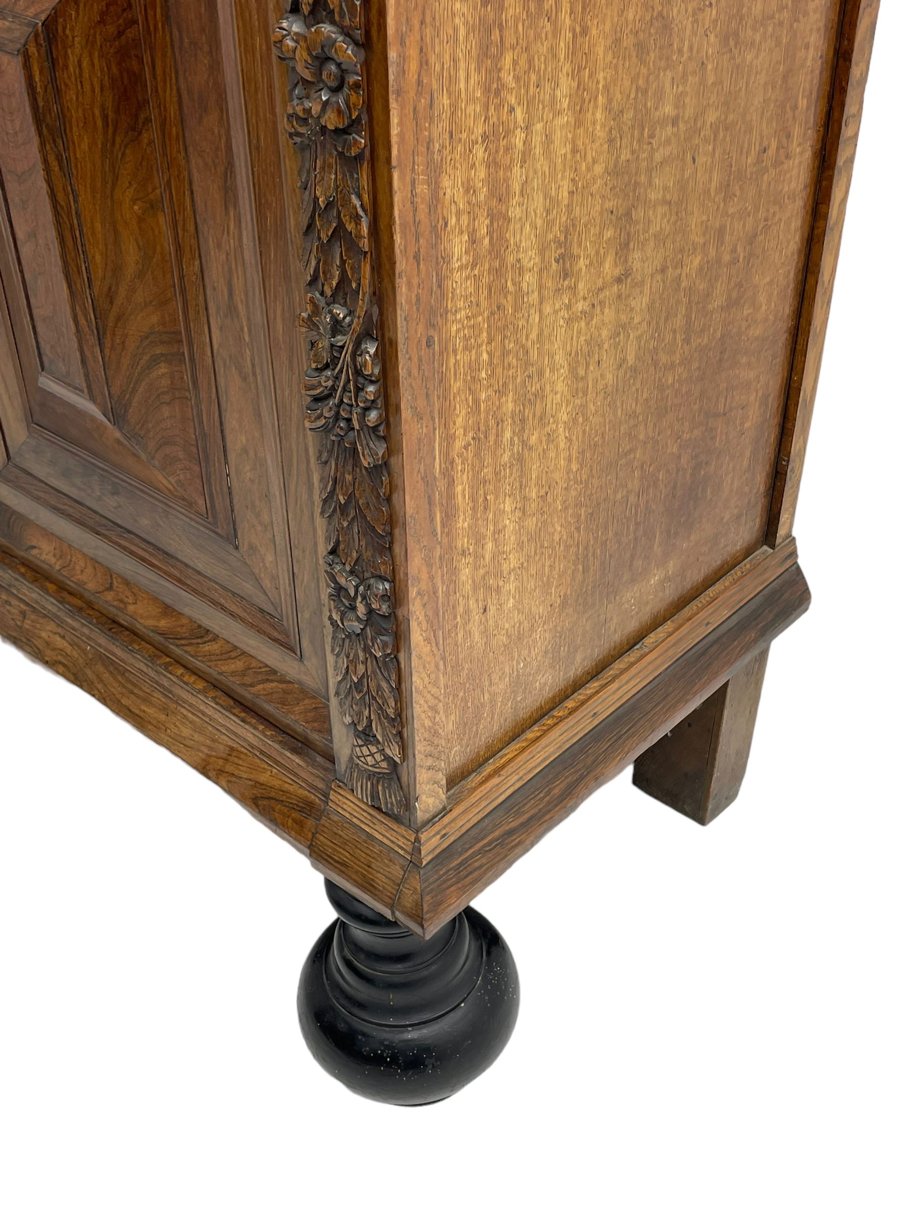 Late 17th century Flemish/Dutch rosewood and oak ‘Zeeuwse Kast’ or cupboard, projecting cornice carved with three putti masks, the uprights carved with lion masks over ribbons, flower heads and foliage, enclosed by four geometric panelled doors, lower central upright carved with flower head over foliate ribbon with bird among foliage, the escutcheon hidden by swivel berry carved cover, interior fitted with shelves, two drawers and shallow hinged cupboard, on two large turned and ebonised feet, circa 1680