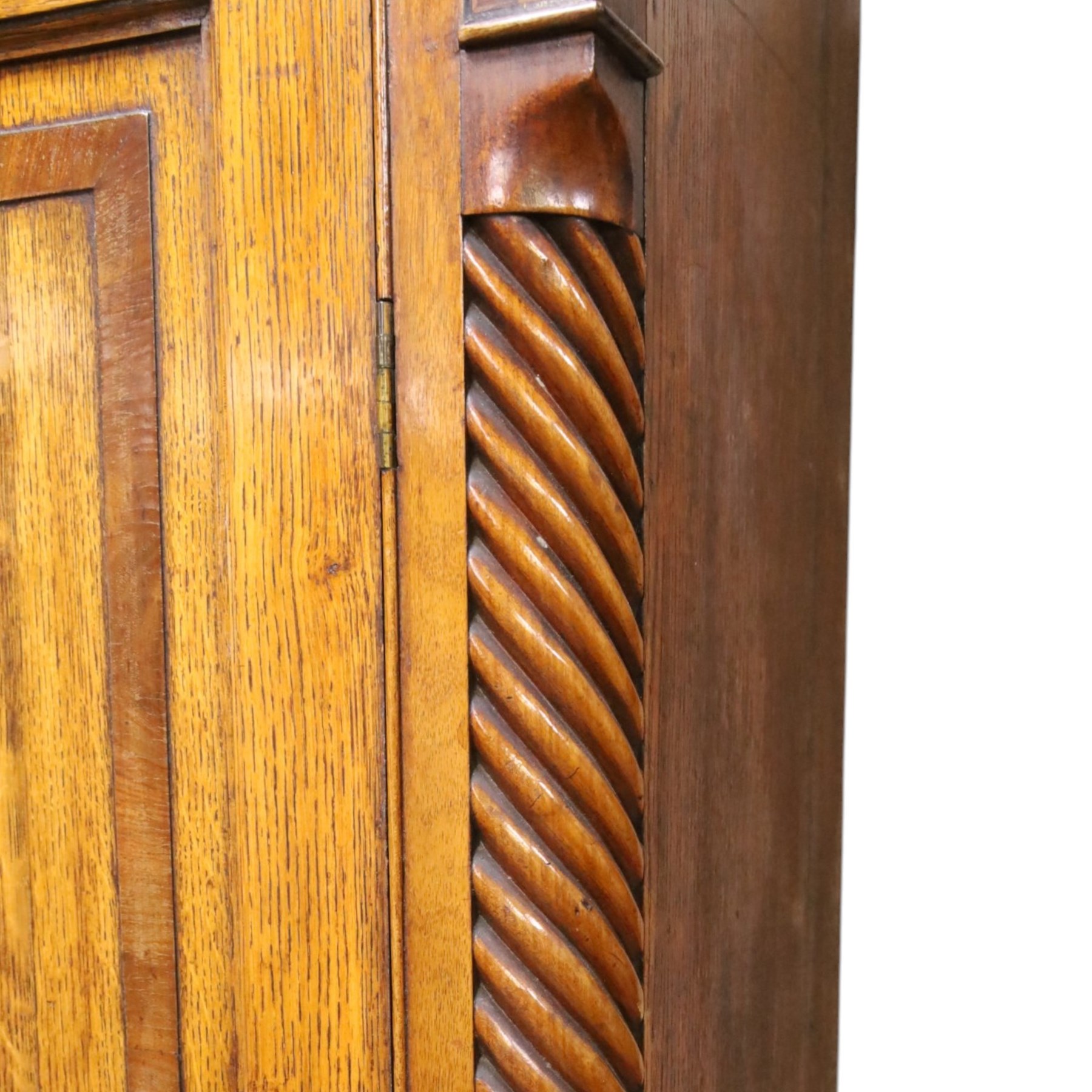 Georgian oak and mahogany housekeepers cupboard, the upper section with projecting cornice, crossbanded and inlaid frieze, above panelled doors with bone escutcheons, enclosing three fixed shelves, flanked by barley twist quarter pilasters, the lower section with further crossbanded and inlaid frieze, two short over two long graduating drawers with ebonised handles, raised on turned supports 