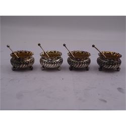 Set of four Victorian silver open salts, each of circular part fluted form with crimped rim, upon three ball feet, and four conforming salt spoons with crimped bowls, hallmarked Thomas Hayes, Birmingham 1887, in fitted case with maroon velvet and silk lined interior, approximate silver weight 3.79 ozt (118 grams)