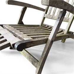 Pair of teak reclining garden steamer armchairs, each with an adjustable slatted back, curved slatted seat and footstool