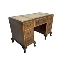 Early to mid-20th century walnut writing desk, inset leather top with foliate carved edge, fitted with seven drawers with brass handles, on shell carved cabriole feet