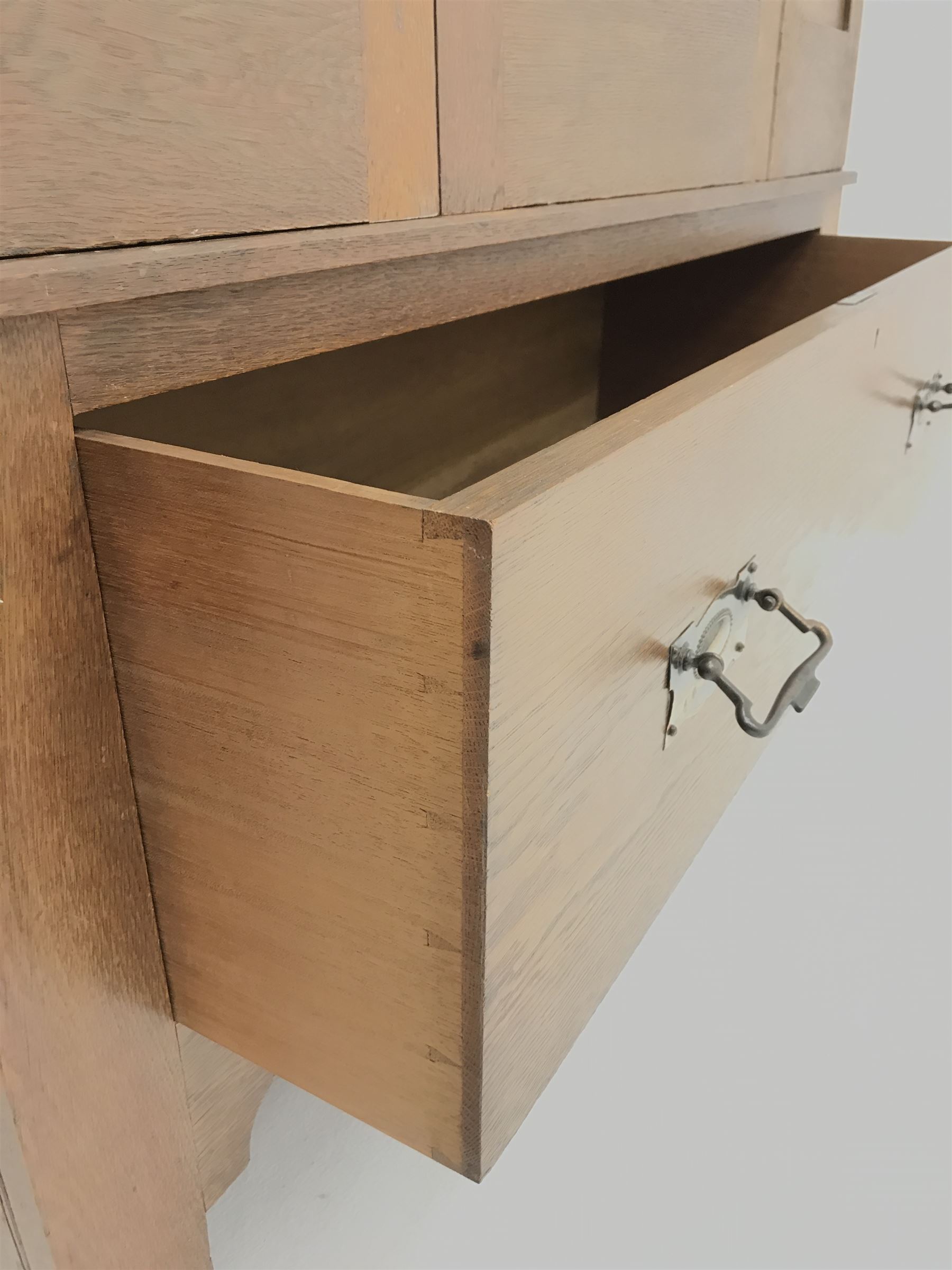 Arts and Crafts period oak wardrobe, projecting shaped cornice, single bevel edged mirrored door above drawer