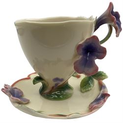 Two Franz teacups and saucers, decorated with flowers, one with matching teaspoon