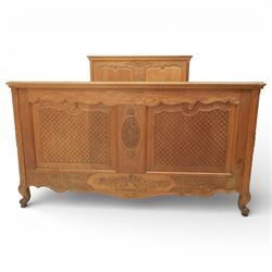 Early 20th century French oak double bedstead, the shaped and moulded headboard carved with central floral cartouche and scrolling foliage above lattice carved panels, the conforming footboard with pierced and carved decoration, shaped apron with foliate carving, raised upon cabriole supports