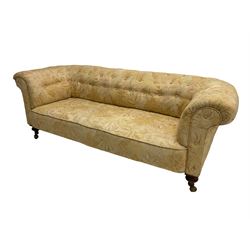 Early 20th century Chesterfield sofa, upholstered in buttoned coral and beige foliate patterned fabric with sprung seat, raised on turned supports with castors