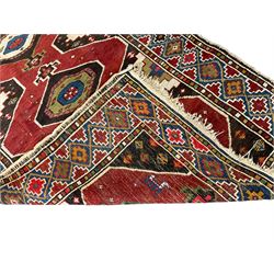 Anatolian Turkish red ground rug, decorated with three central lozenges, the multi-colour guarded border with repeating geometric shapes