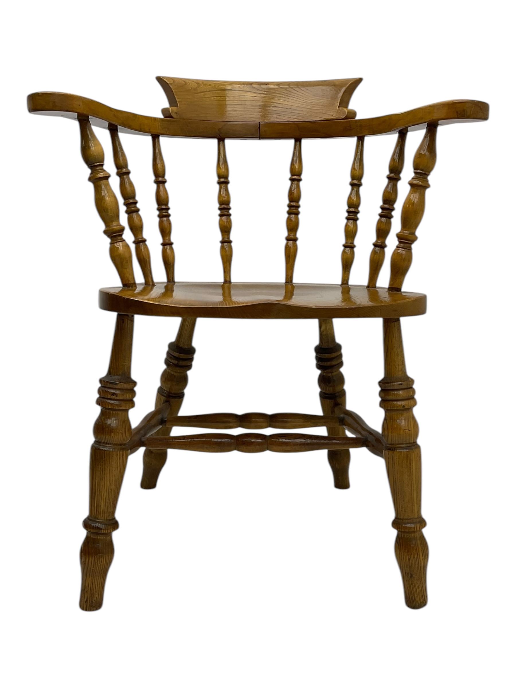 Late 19th century elm smoker’s bow armchair, curved top rails over turned spindle backs, shaped seats, raised on turned legs united by turned stretchers; together with a similar smoker’s bow armchair (2)