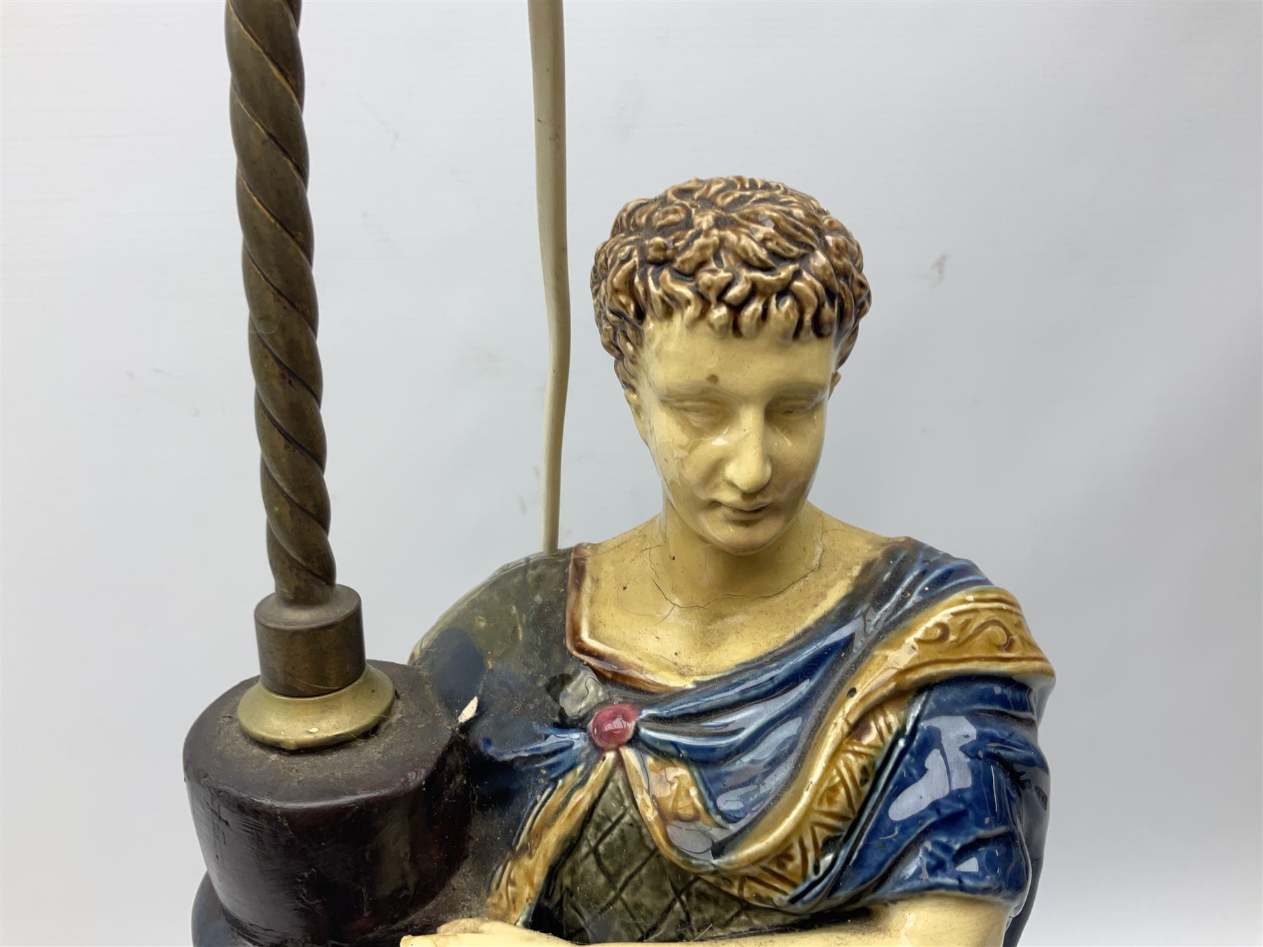 Composite table lamp modelled as a Roman Emperor donning blue robes, upon quatrefoil base modelled with rams heads and winged cherubs, H56cm excl fitting