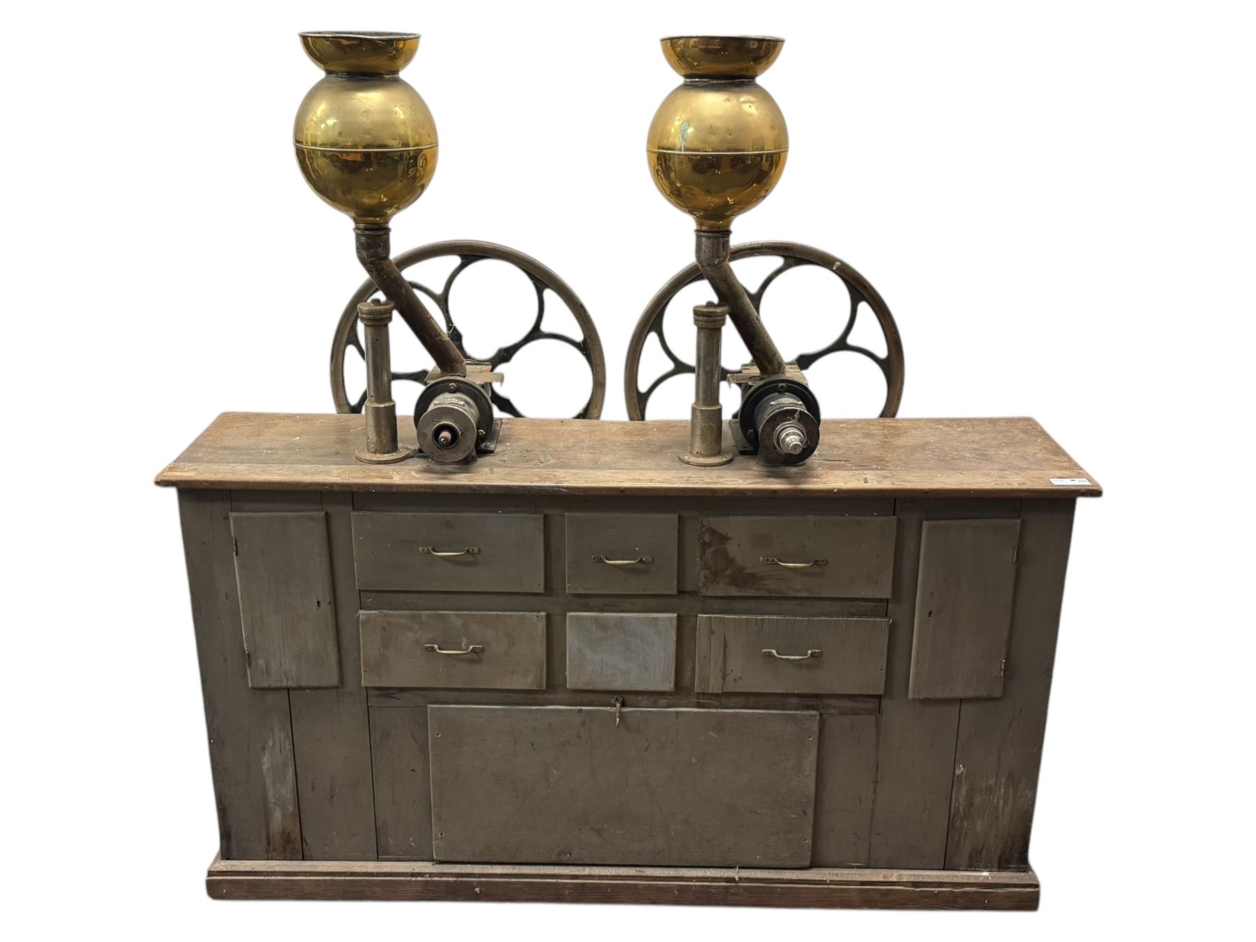Cabinet with multiple drawers and cupboards mounted with two industrial coffee grinders with large flywheels and brass coffee reservoirs, early 20th century 