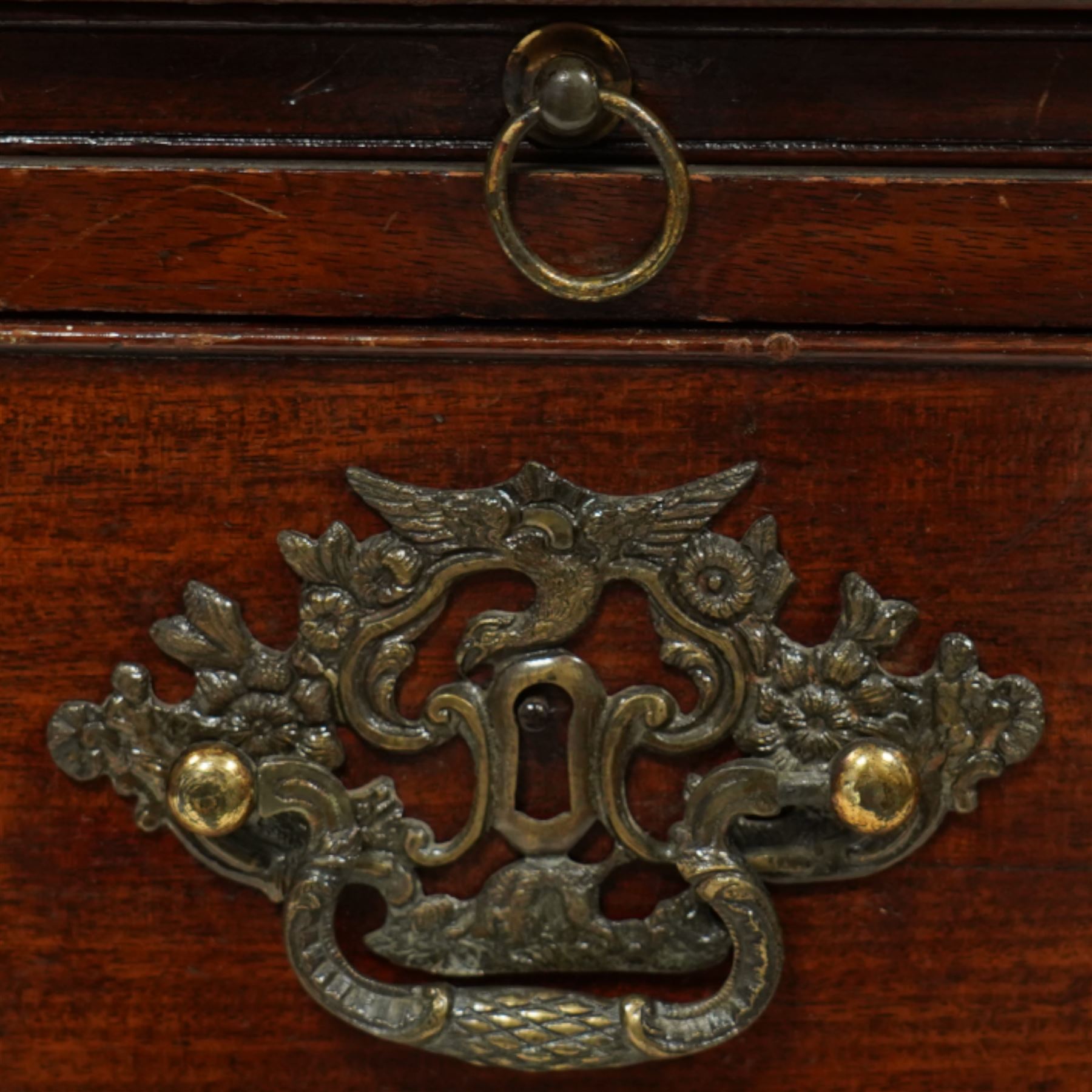 Early 20th century mahogany chest, rectangular top with raised gallery back with brushing slide on sliding tray, fitted with two cupboard doors behind six false drawer fronts, pierced brass handles on a plinth base