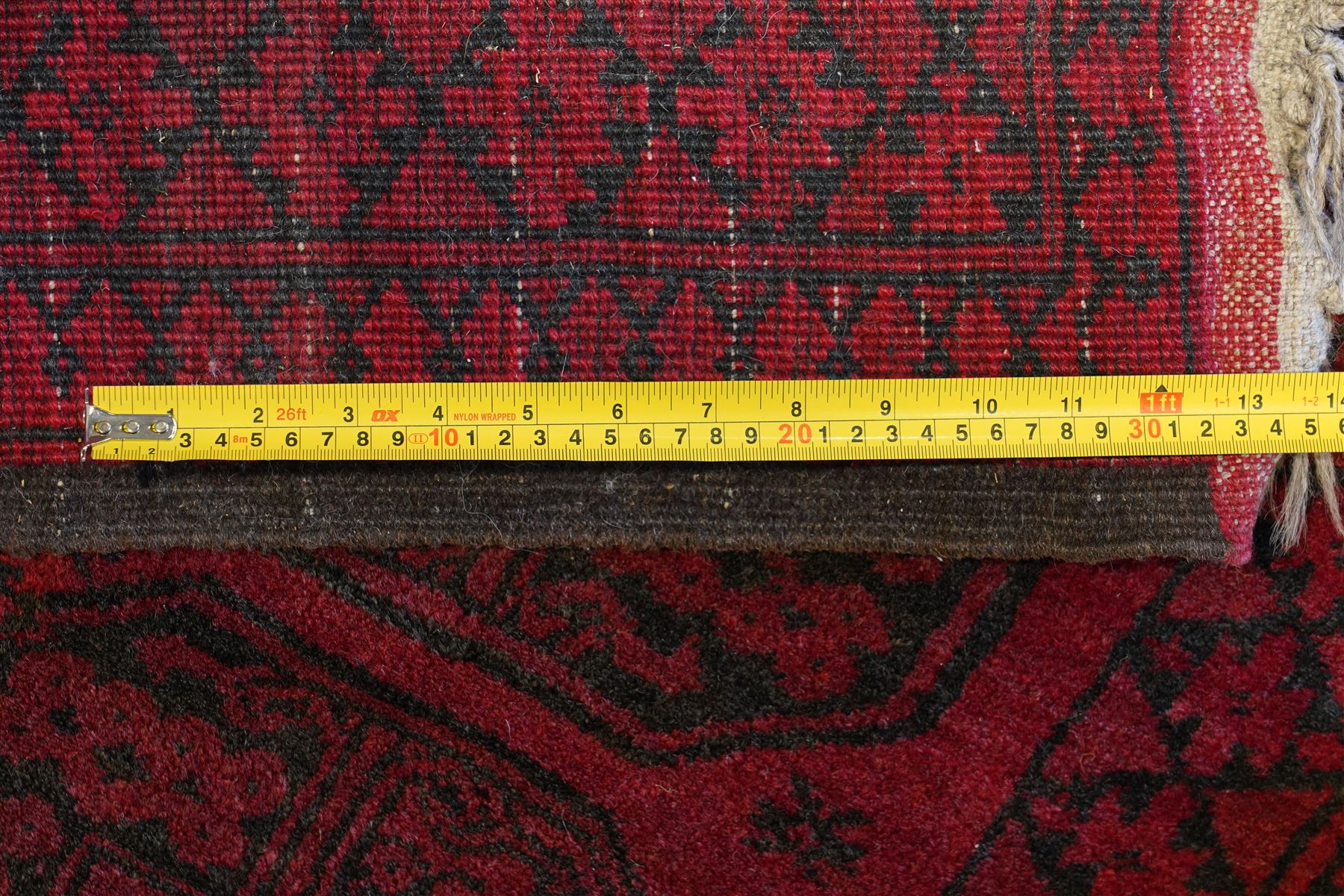 Afghan crimson ground Bokhara rug, the field with three rows of repeating Gul motifs, within six concentric guard bands decorated with repeating geometric patterns
