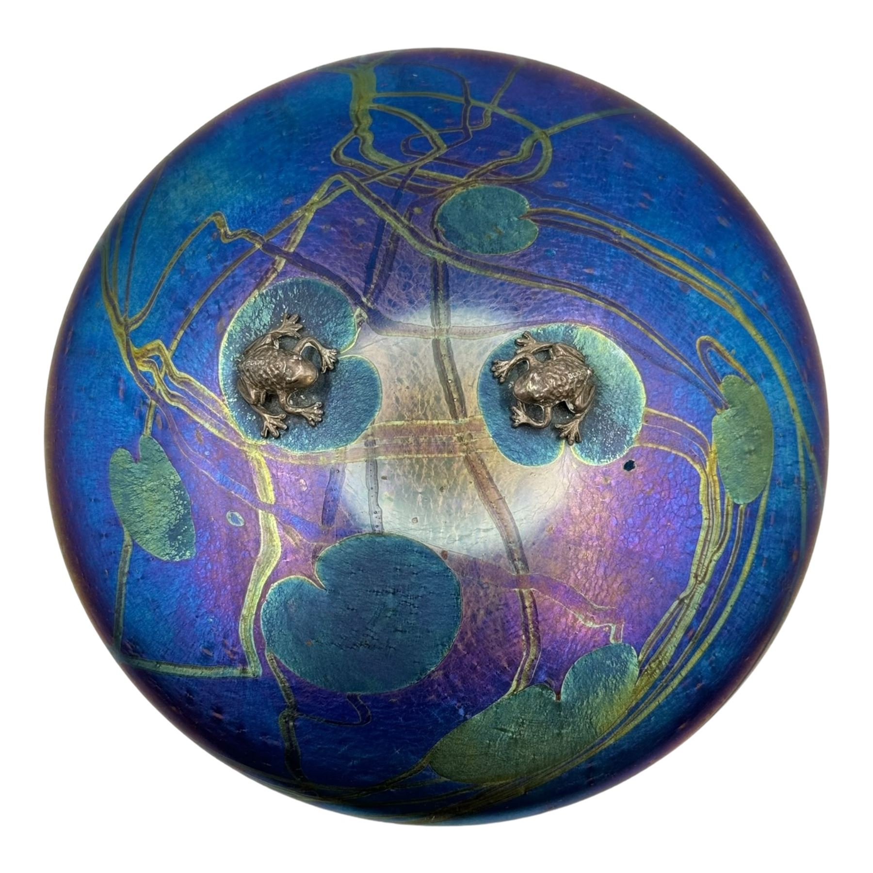 John Ditchfield for Glasform disc paperweight in iridescent purple with green lily trail and a pair of silver hallmarked frogs to top, D14cm