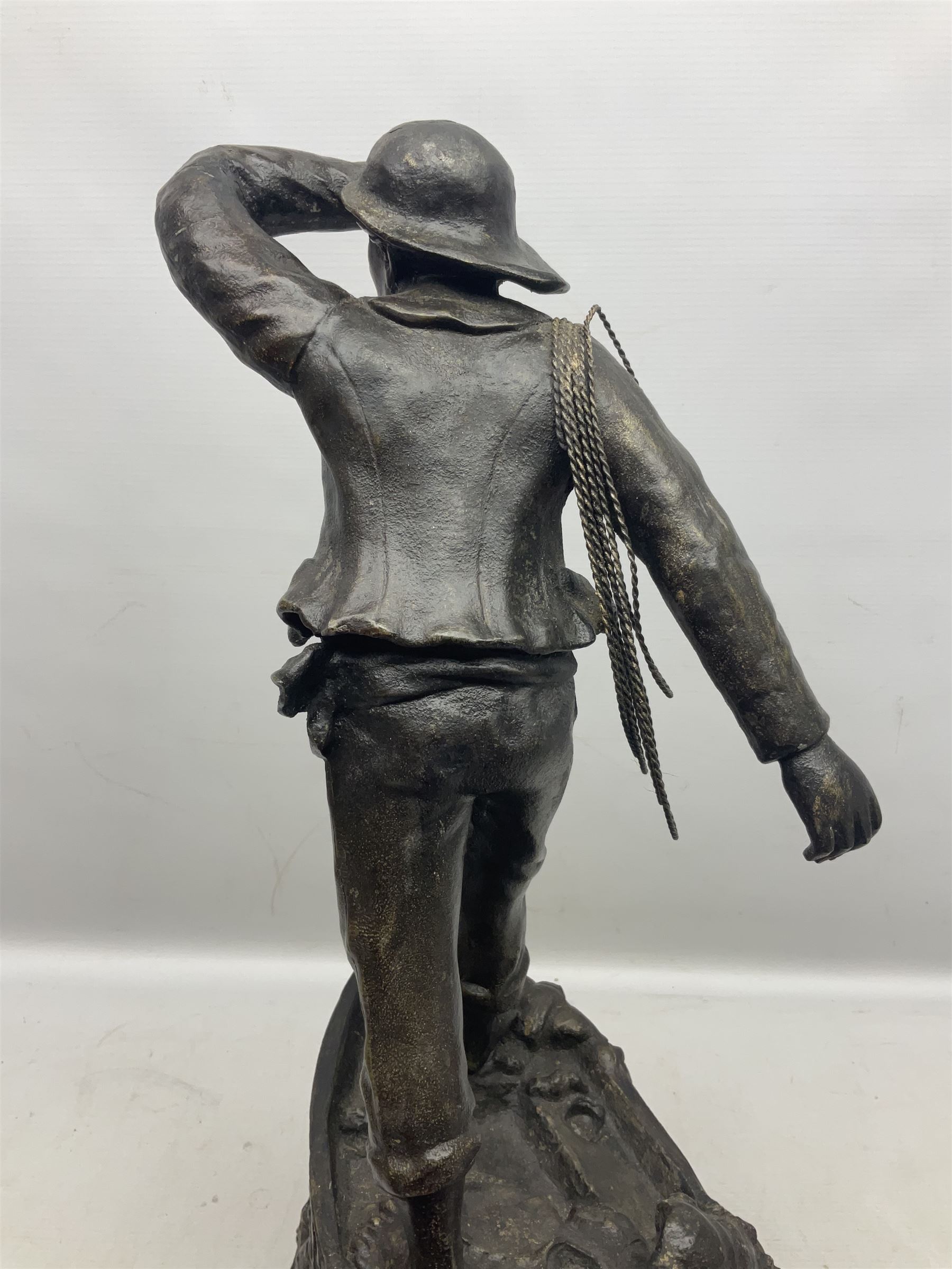 Early 20th century spelter effect figure of a sailor standing in the bow of a boat scanning the horizon, on a simulated rock base with a plaque entitled 'Rescue', base fitted with a timepiece clock movement and two-part dial, with pierced hands, gilt dial centre and ivorene chapter ring written in Arabic numerals, German HAC spring driven going barrel movement wound from the front; with pendulum H65.5cm

