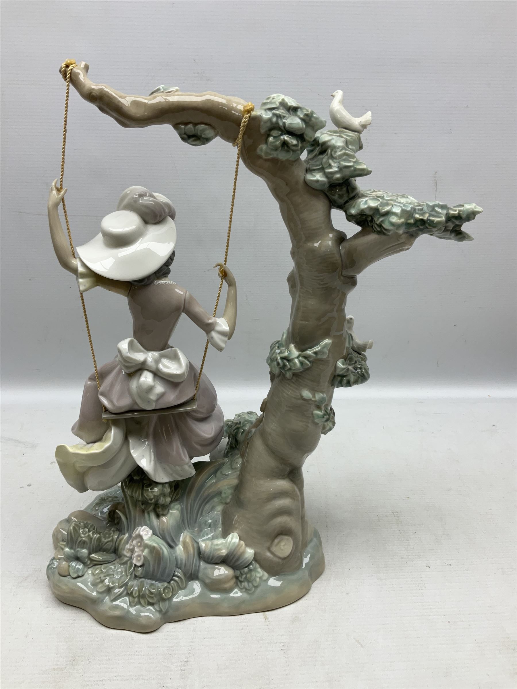 Lladro figure, Swinging, modelled as a woman sat on a swing attached to