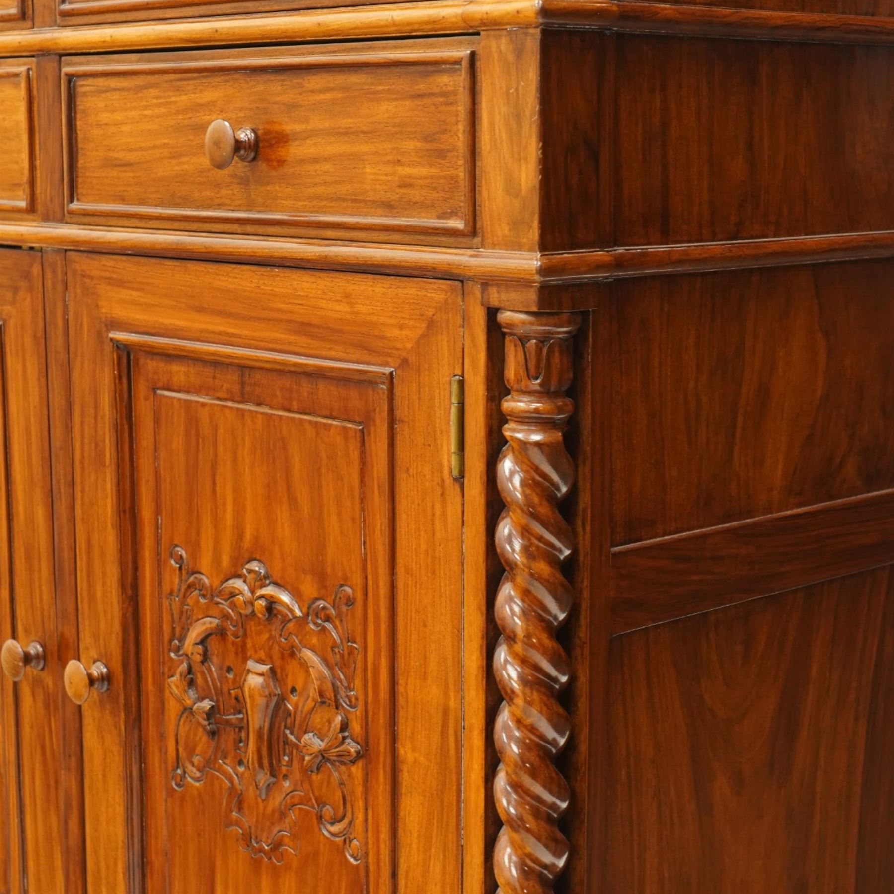 Victorian design rosewood side cabinet, the rectangular moulded top above four frieze drawers with turned wooden knob handles, over twin cupboard doors carved with foliate panels, flanked by barley twist uprights, upon turned bun feet
