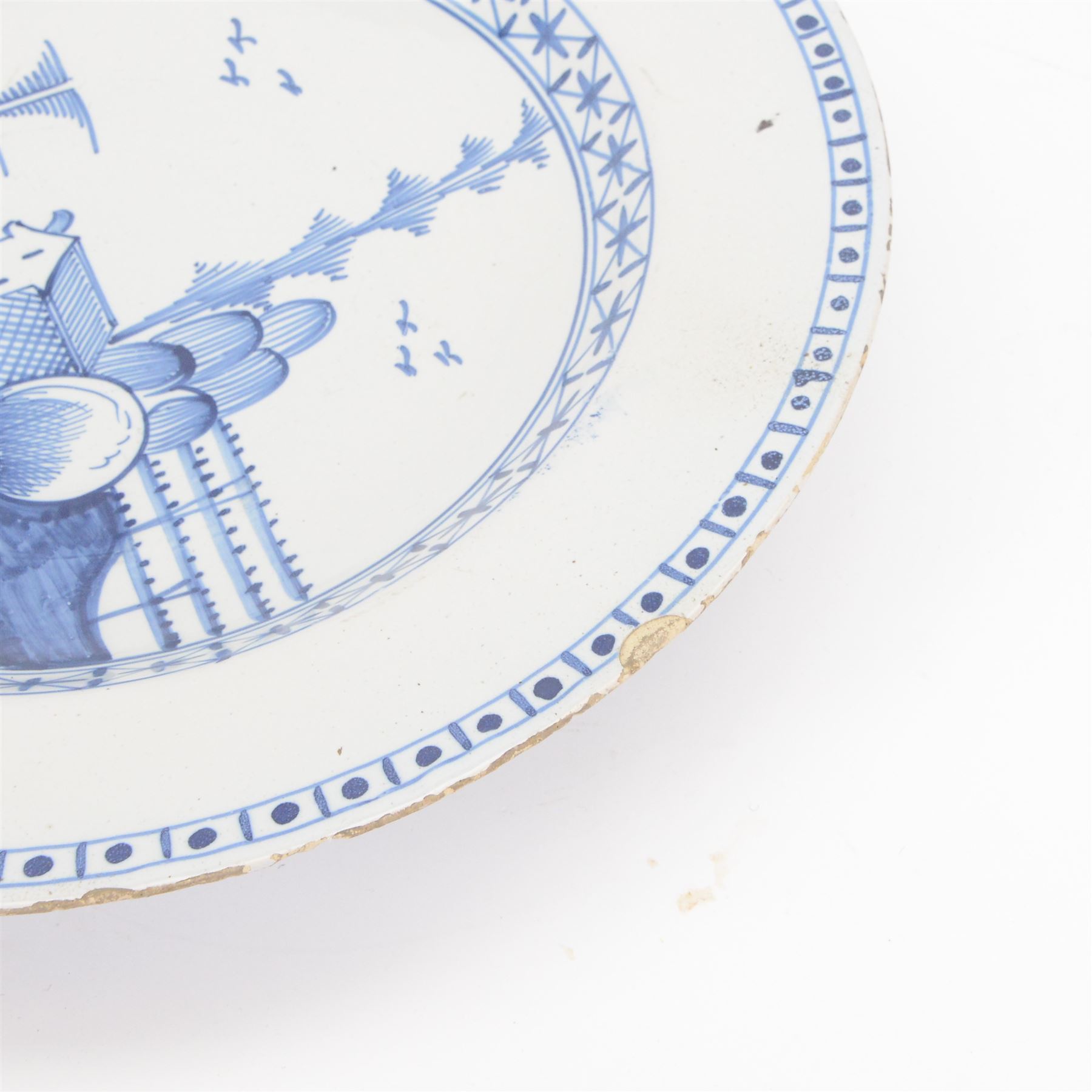 Mid 18th century Lambeth Delft plate, probably from the Abigail Griffith factory, circa 1750, painted in polychrome enamels with a figure seated in a landscape, within a garlanded border of flowers to rim, D34cm, together with a Liverpool Delft plate, circa 1760, painted in blue with a boathouse surrounded by trees by a river, within diaper and cell borders, D37cm