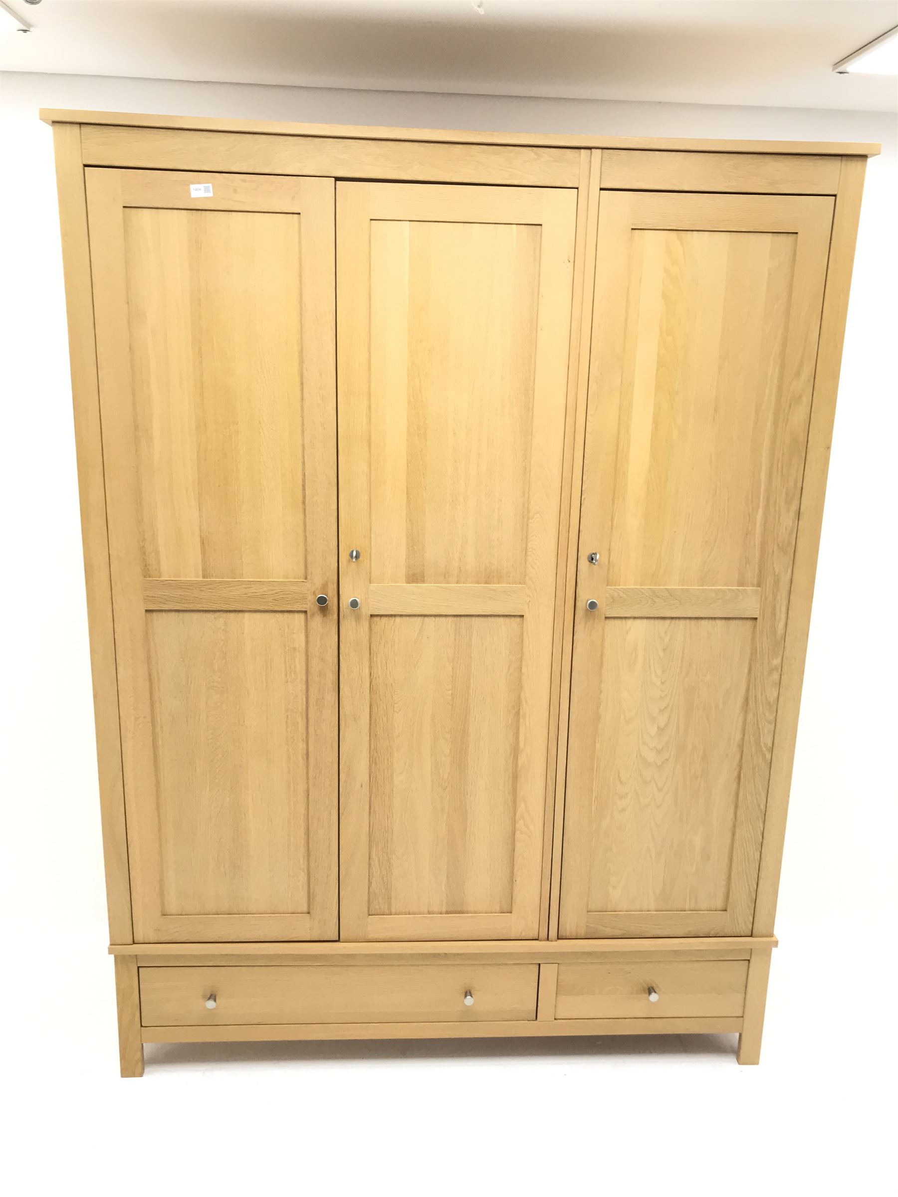Light oak triple wardrobe, projecting cornice, three doors enclosing fitted interior above one long and one short drawer, stile supports 