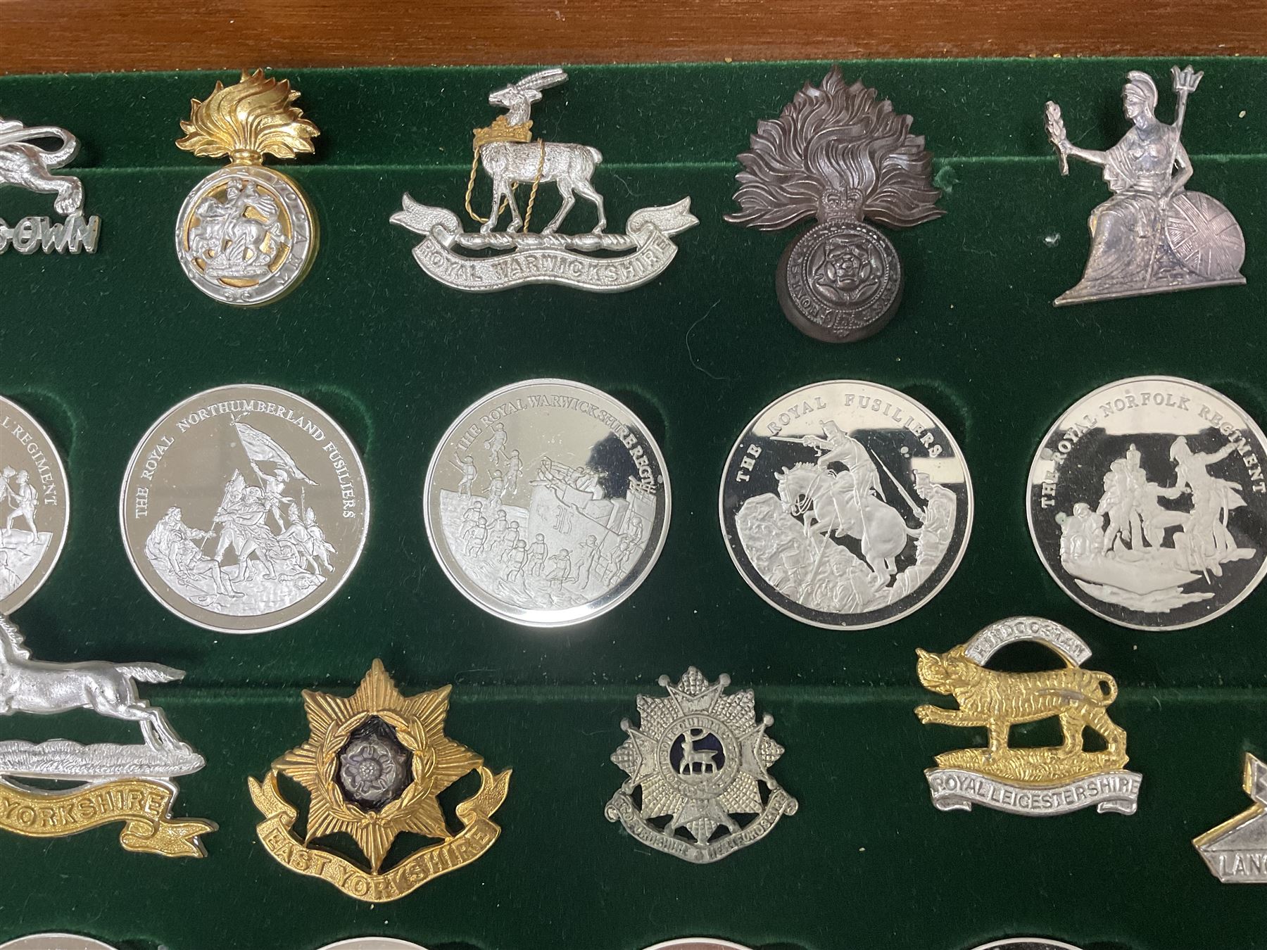 Great British Regiments, 1977, set of fifty two frosted silver medals by the Birmingham Mint, each bearing the name of a regiment with a depiction of an action on the obverse and further details on the reverse, all hallmarked Birmingham Mint, assay offices and dates; together with 52 base metal copy cap badges for each regiment, all housed and mounted on two trays and contained within a wooden presentation case, with brass plaque and fittings, lock and key, with a certificate of authenticity 