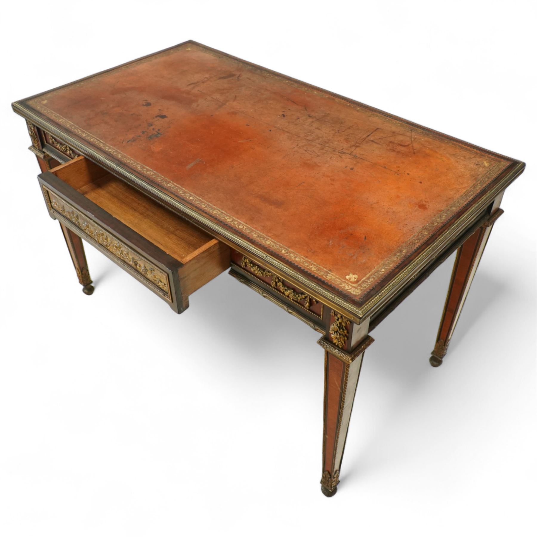Fine 19th-century Louis XVI-style mahogany and gilt bronze-mounted writing table, rectangular top with a gilt tooled tan leather writing surface within a moulded gilt bronze edge above a frieze fitted with three drawers, mounted with floral and foliate gilt bronze swags  and borders, raised on square tapering legs with acanthus mounts and toupie feet