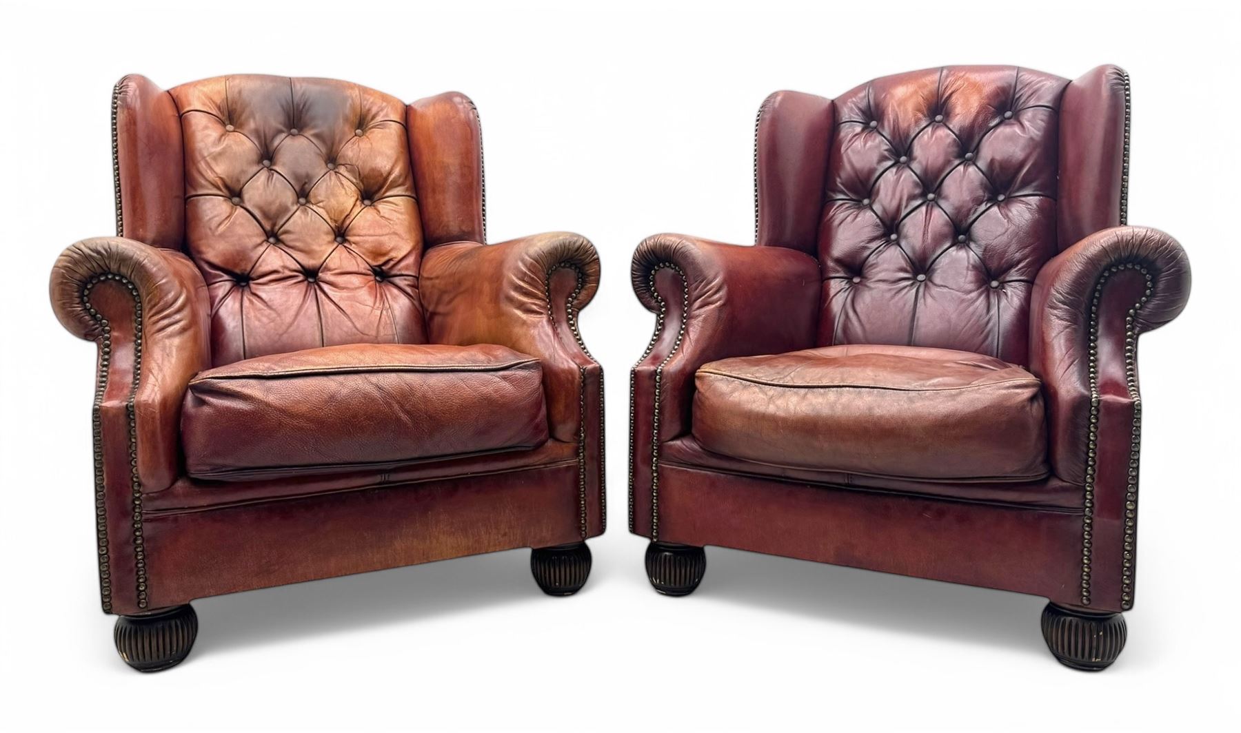 Tetrad - pair of 'Oskar' wingback armchairs, deep-buttoned oxblood leather upholstery with rolled arms and brass stud trim, raised on turned and reed moulded feet