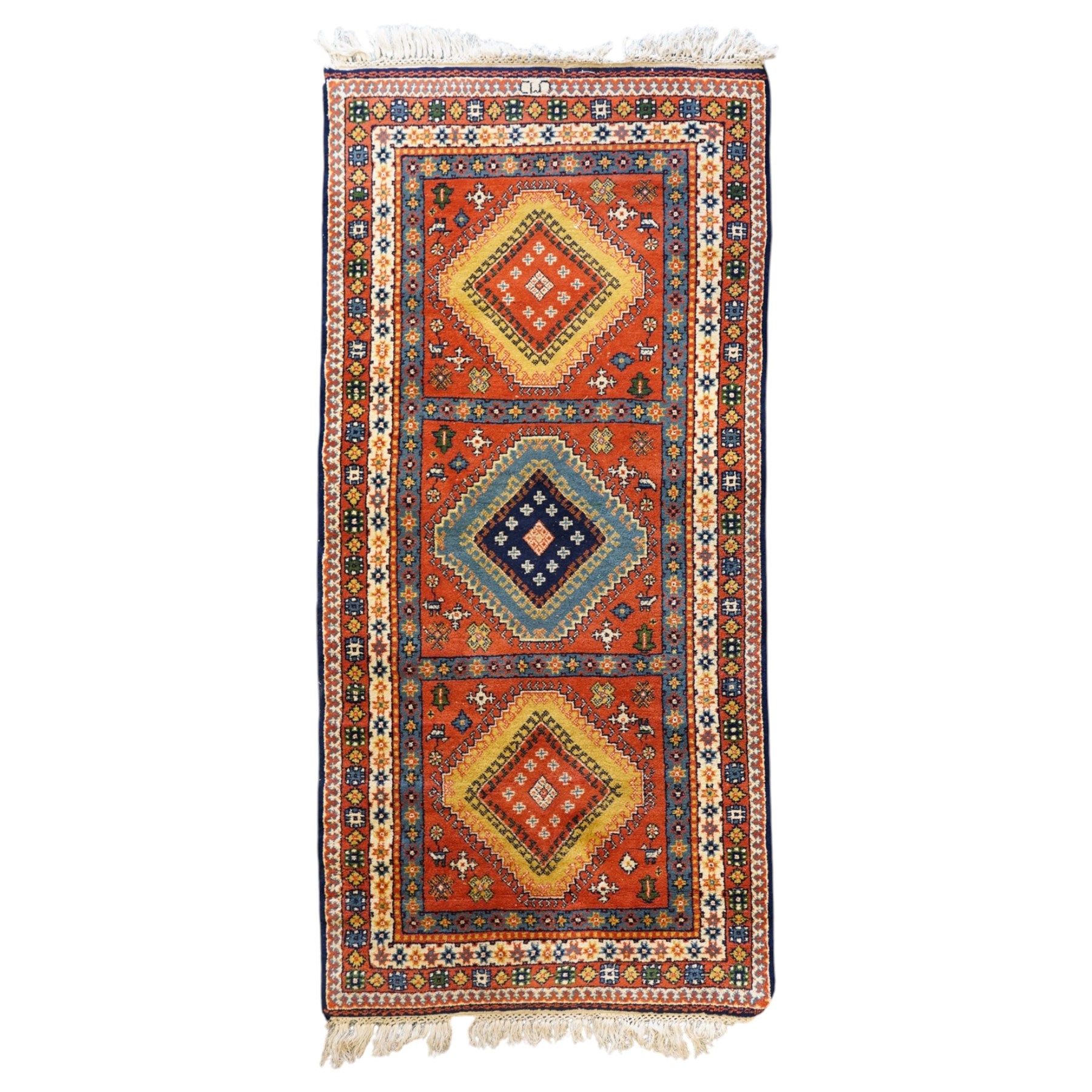 Caucasian Kazak vermillion ground rug, the sectioned field decorated with three geometric lozenge medallions surrounded by stylised plant and animal motifs, the multiple guard bands with repeating geometric design