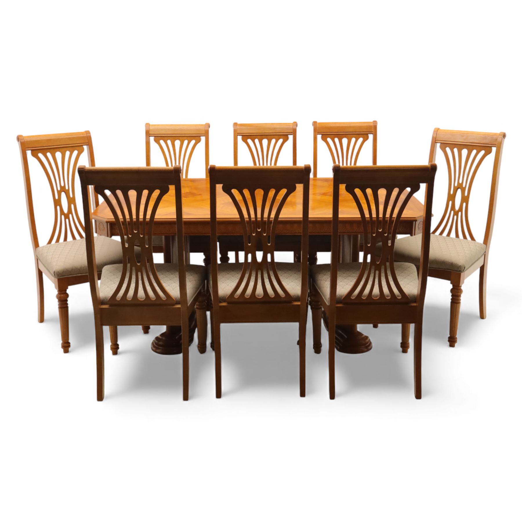 Late 20th century parquetry veneered extending dining table and eight chairs, the rectangular top with canted corners decorated with geometric parquetry panels, moulded edge frieze with repeating carved detail, raised on twin pedestal supports with fluted columns and shaped platform bases, the chairs with pierced splat backs and upholstered drop-in seats
Extends on a central leaf to 208cm