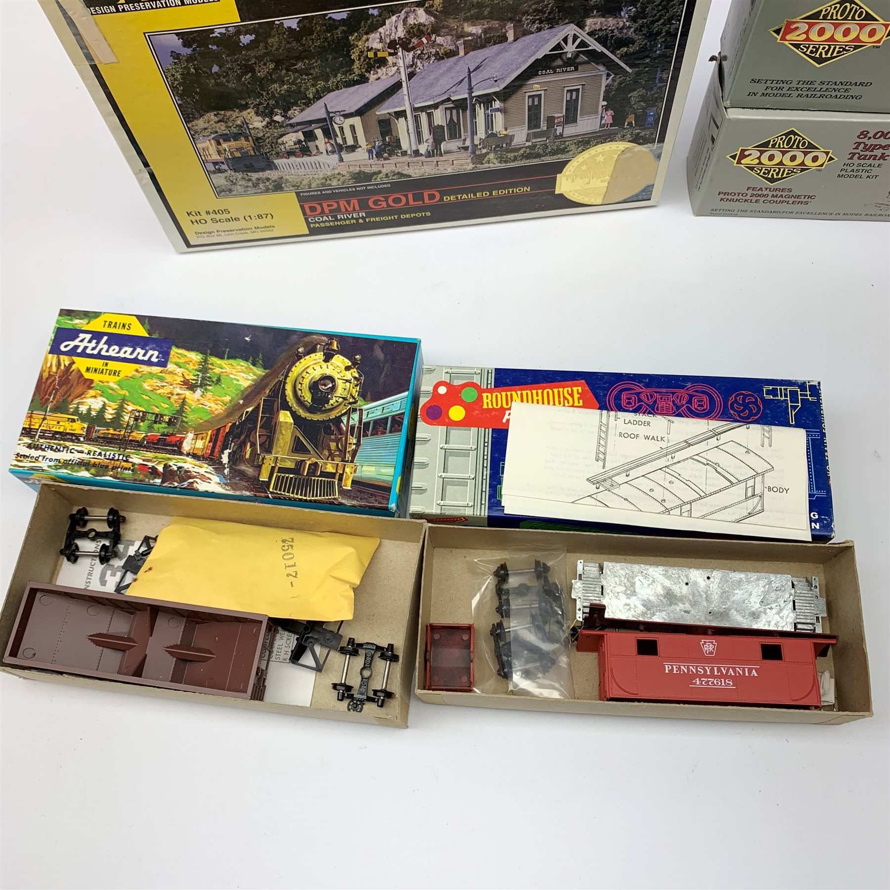 HO scale - nine American goods wagon plastic construction kits comprising three Proto 2000 Series Mather 40' Single Deck Stock Cars and 50 ton War Emergency Hopper, two Tichy Train Group 4024 Wood Reefers, two Athearn hopper wagons and Roundhouse Caboose; together with DPM Gold Coal River Passenger and Freight Depots and two Langley Miniature Models lorry kits, all boxed (12)