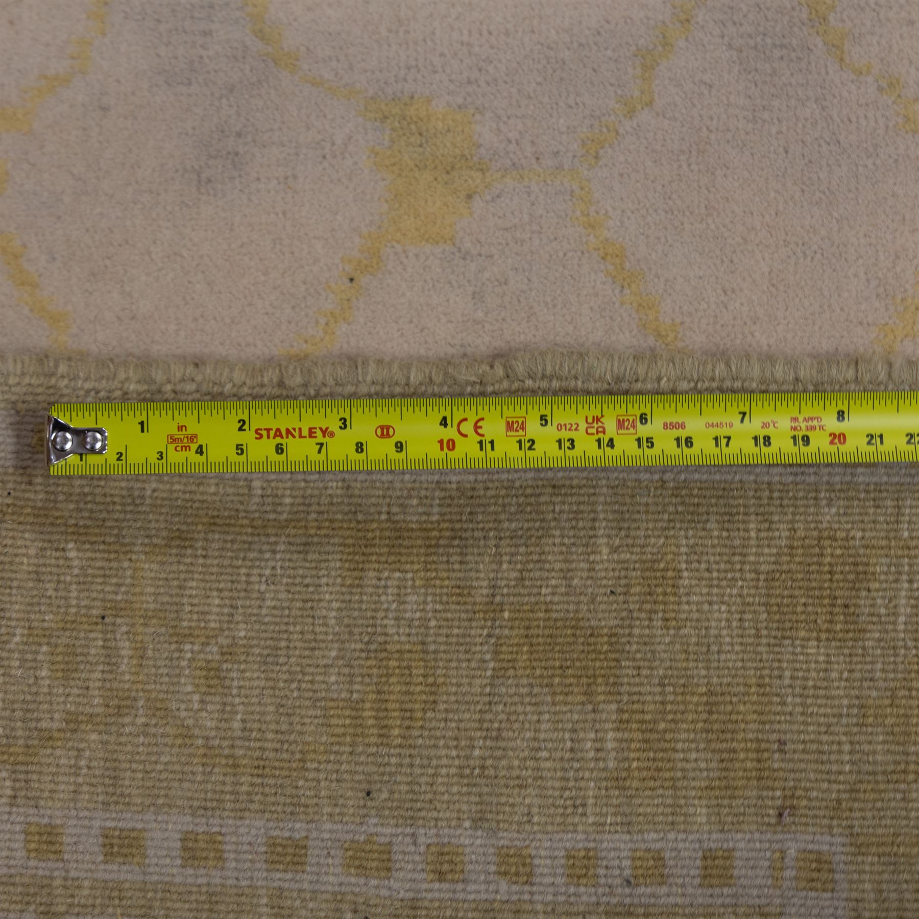 Tibetan wool rug, decorated with a pale cream ground and yellow all-over foliate design, enclosed by a broad yellow floral border and narrow inner guard band