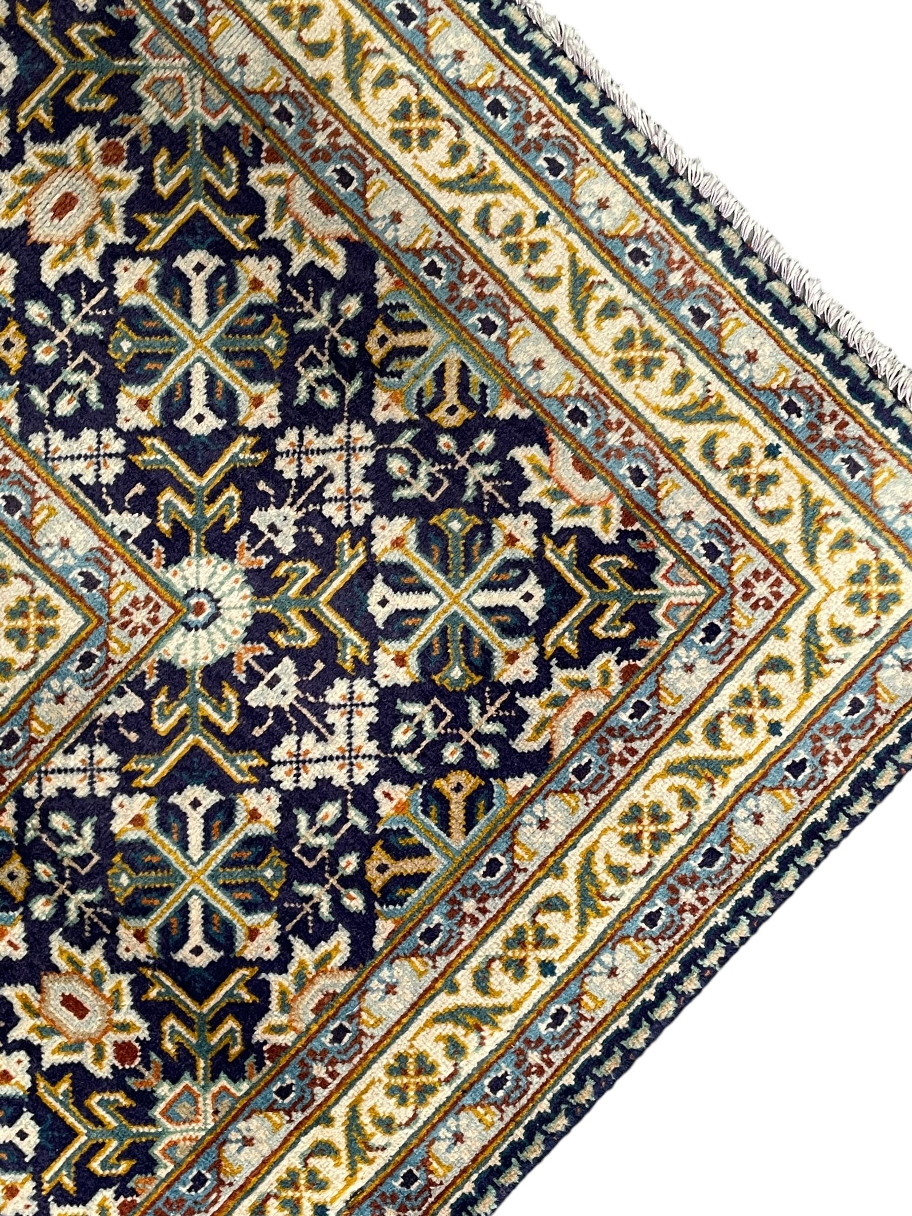 Persian indigo and pale gold ground rug, overall busy geometric design, the field decorated with hooked Hac and palmette medallions surrounded by densely patterned zig-zags and stylised foliate motifs, the border decorated with smaller Hac motifs, within multiple guard stripes 