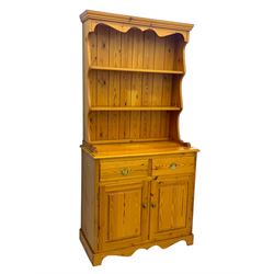 Victorian design pine dresser, projecting moulded cornice over scalloped frieze and two open shelves, base fitted with two drawers over double cupboard, on shaped plinth base