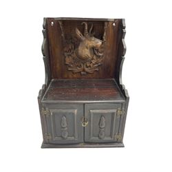 Late 19th century oak wall cabinet, raised back heavily carved with a goat's head surrounded by acanthus leaves and scrolling, fitted with two panelled cupboard doors enclosing three pigeonholes and shelf