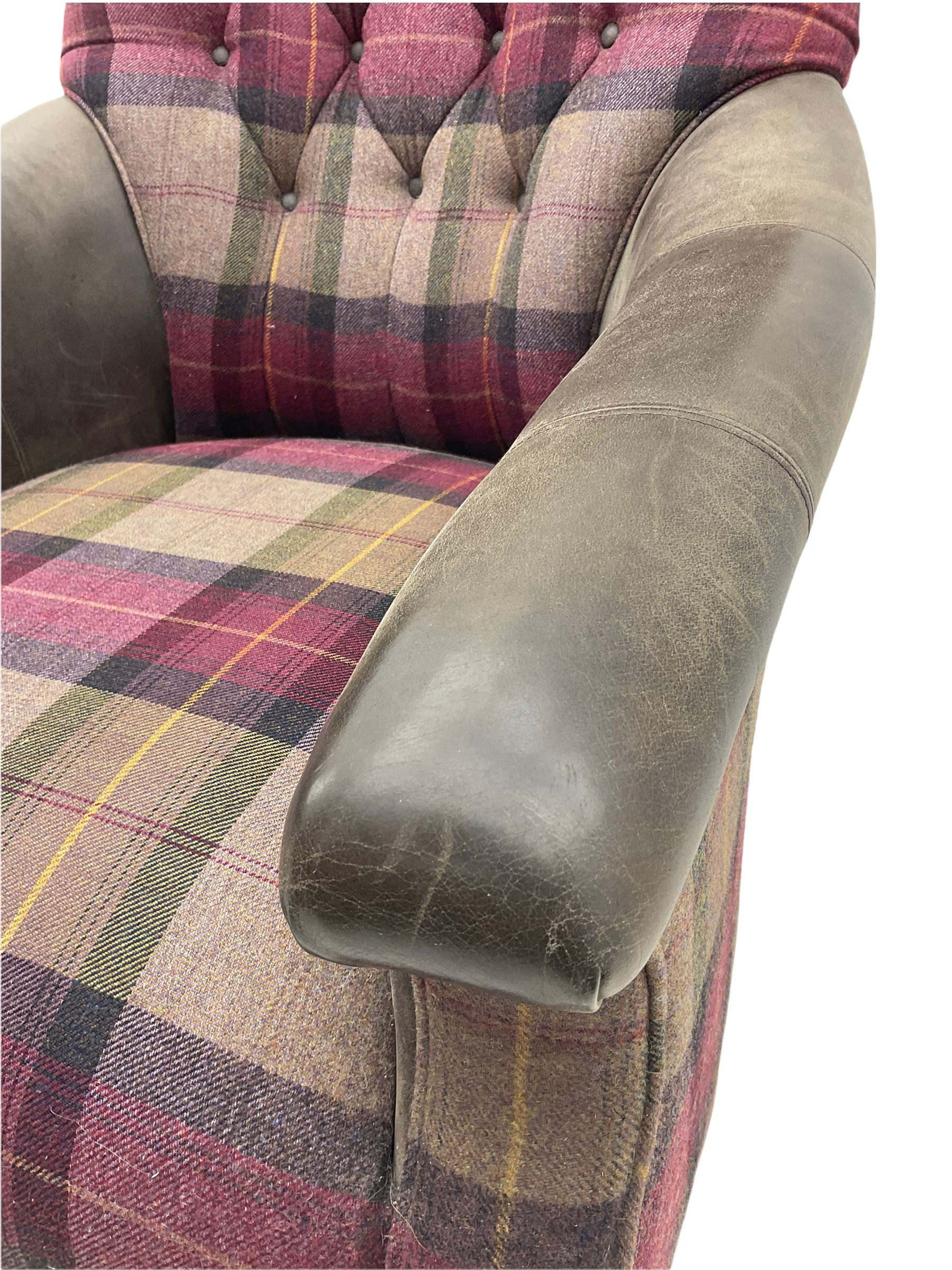 John Sankey - low armchair, buttoned back upholstered in tartan patterned fabric with contrasting grey leather, raised on turned and ebonised front feet with brass and ceramic castors, with matching foot stool