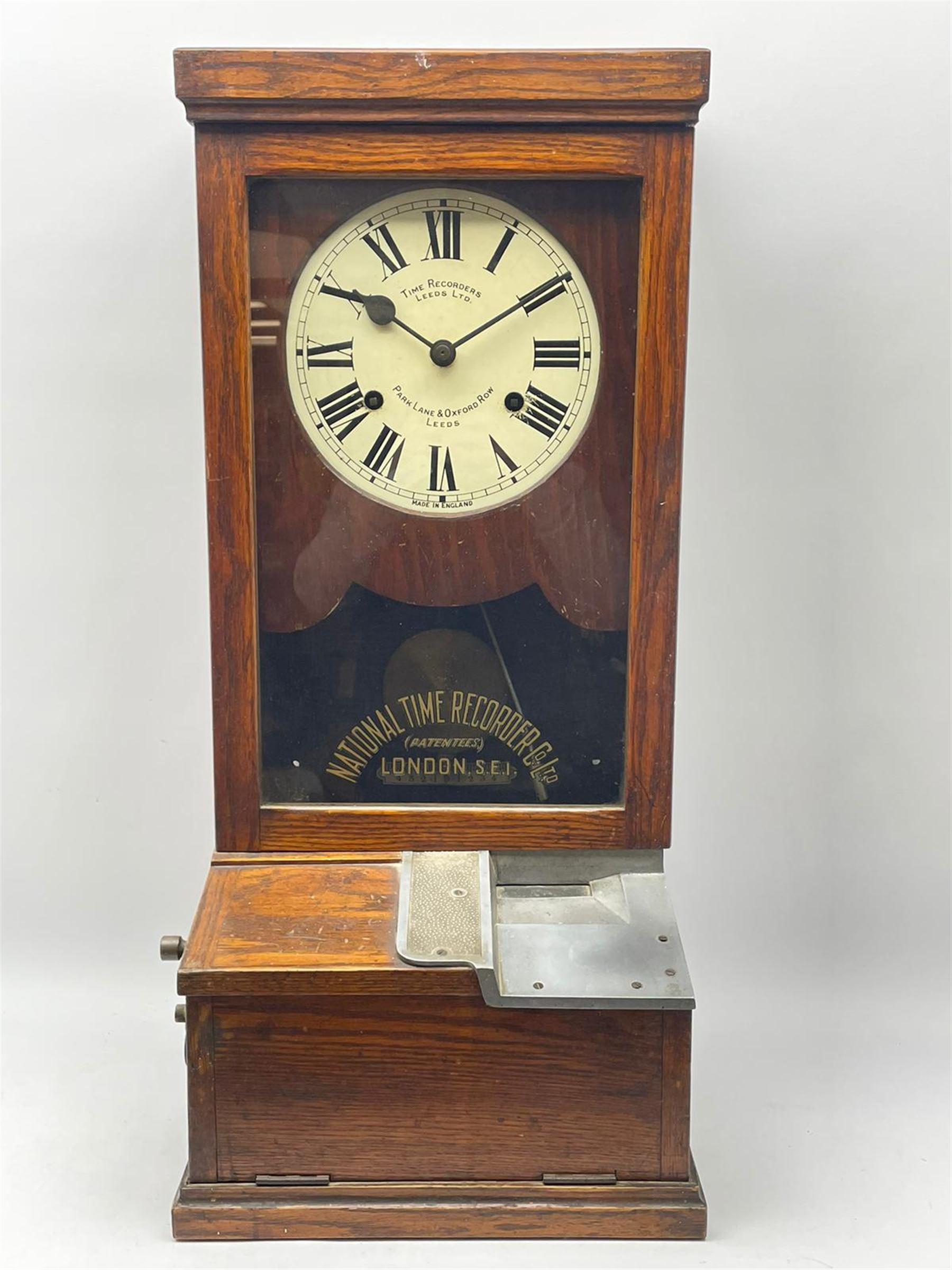 Early 20th century oak cased time recorder, circular Roman dial signed 'Time Recorders Leeds Ltd. Park Lane & Oxford Row Leeds', the glazed door signed 'National Time Recorder Co Ltd. London...'