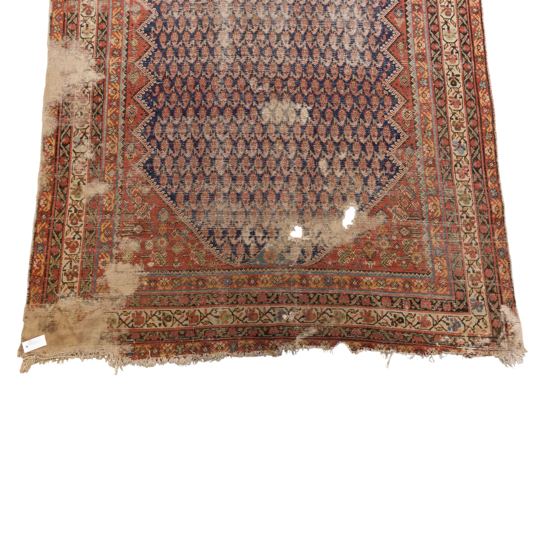 West Persian Kurdish vintage carpet, indigo field decorated with an all-over repeating boteh design arranged in diagonal rows framed by angular spandrels and enclosed by multiple geometric borders in a palette of indigo blue, madder red, soft green and ivory