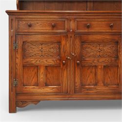 20th century oak dresser, moulded cornice above open plate rack with shaped frieze, flanked by two cupboard doors enclosing shelving, the base fitted with three drawers over three fielded panel cupboard doors, raised on bracket feet