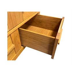 Contemporary light oak triple wardrobe, panelled doors with vertical linear design, left section enclosing hanging rail and single shelf, right section with adjustable shelves, over two drawers, on square stile supports