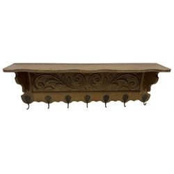 Oak wall hanging coat rack, shape lintel over panelled back carved with foliate S-scrolls, fitted with seven hooks